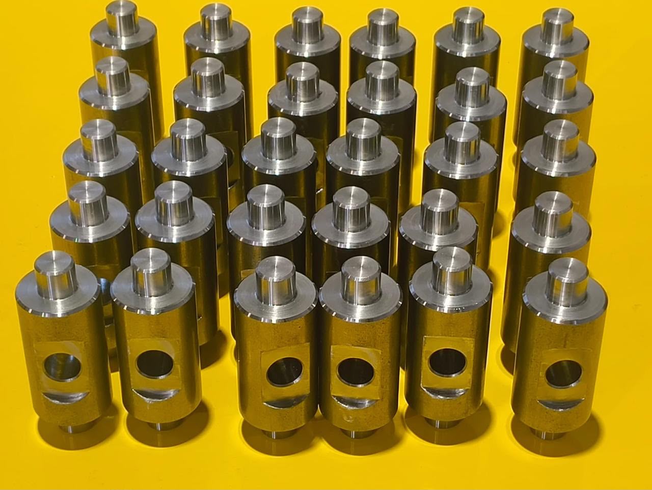 Group of custom-machined metal mechanical parts arranged on a yellow surface.