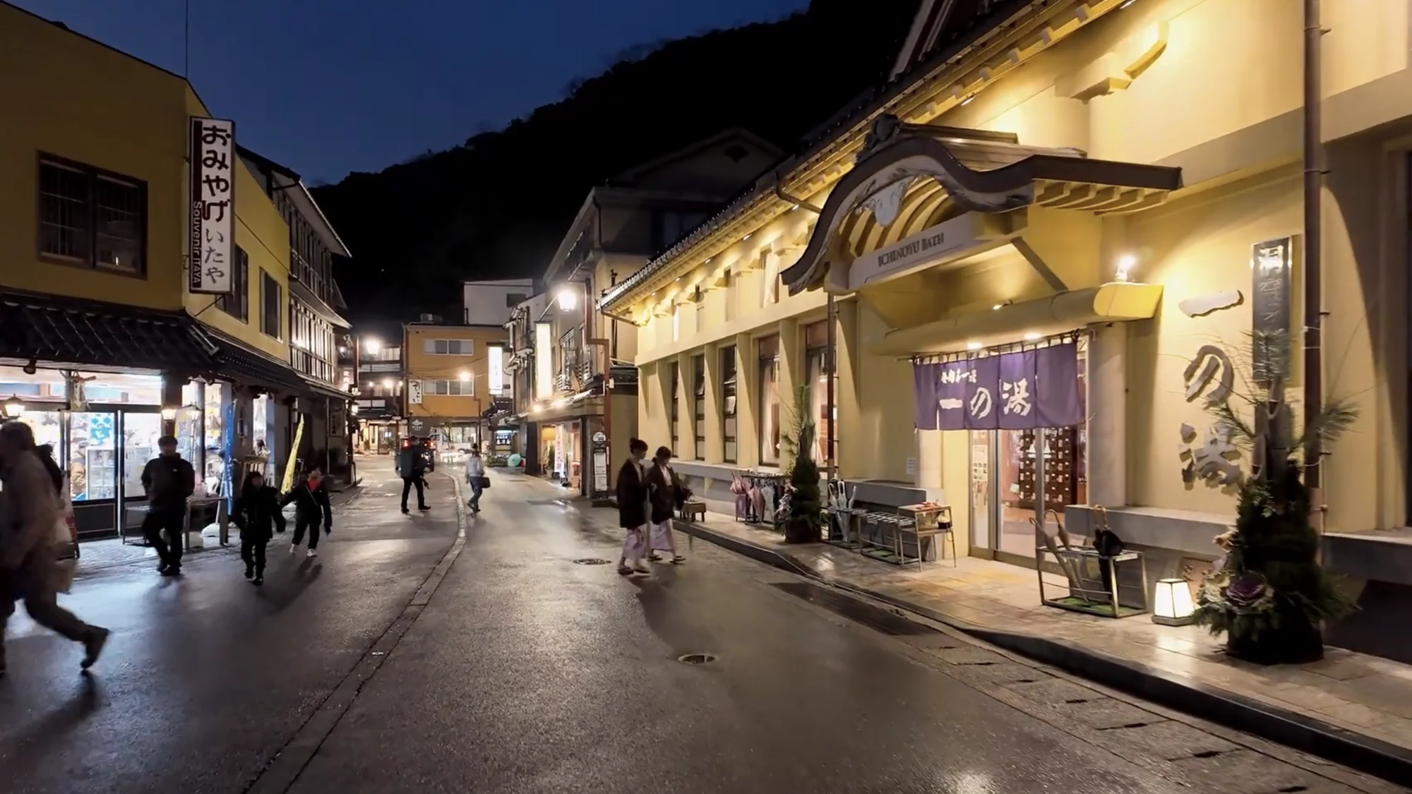 Ichi-no-yu bathhouse lit at night with its noren glowing and the street busy outside.