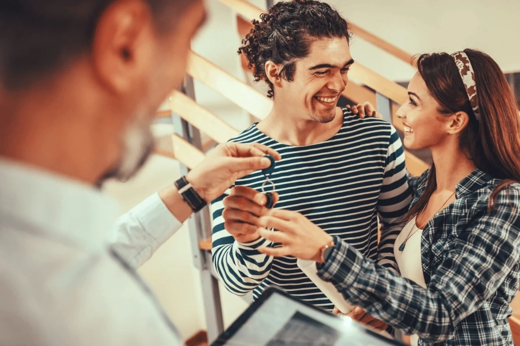 Happy young couple smiling as they receive the keys to their new home.