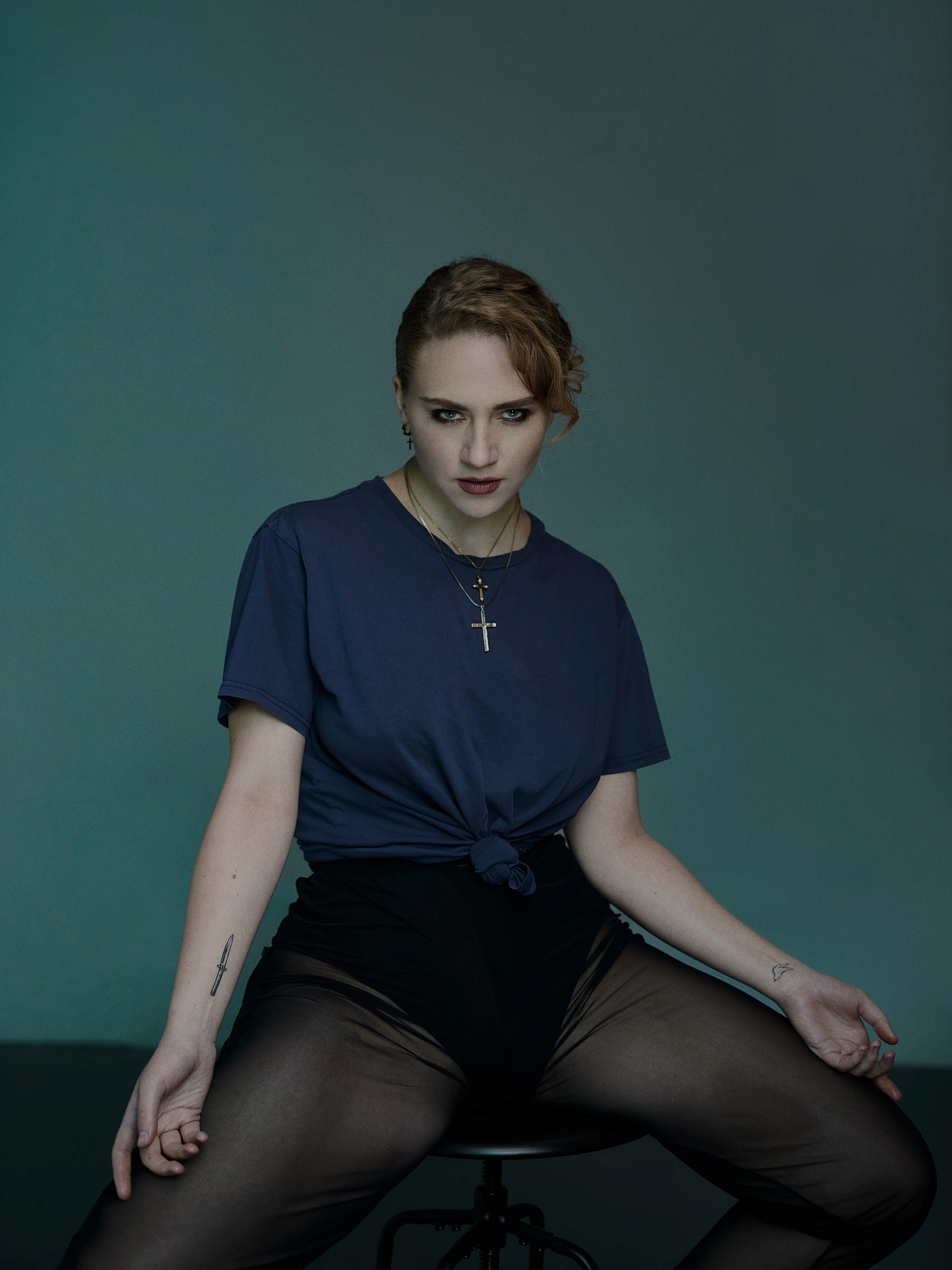 A moody studio portrait of actor, model, dancer and musician Kat Cunning. She is sat in a provocative pose with classical poise.  