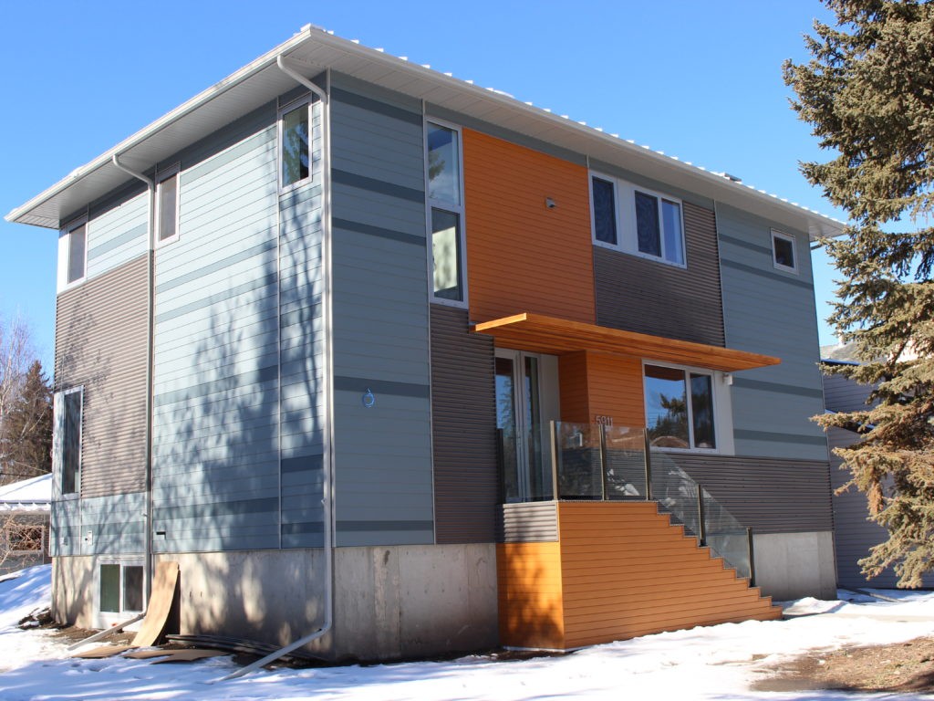 Modern Calgary home with mixed siding and orange architectural accent under winter sk