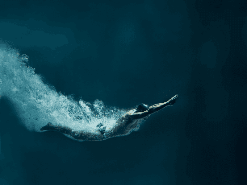 man diving into deep blue water