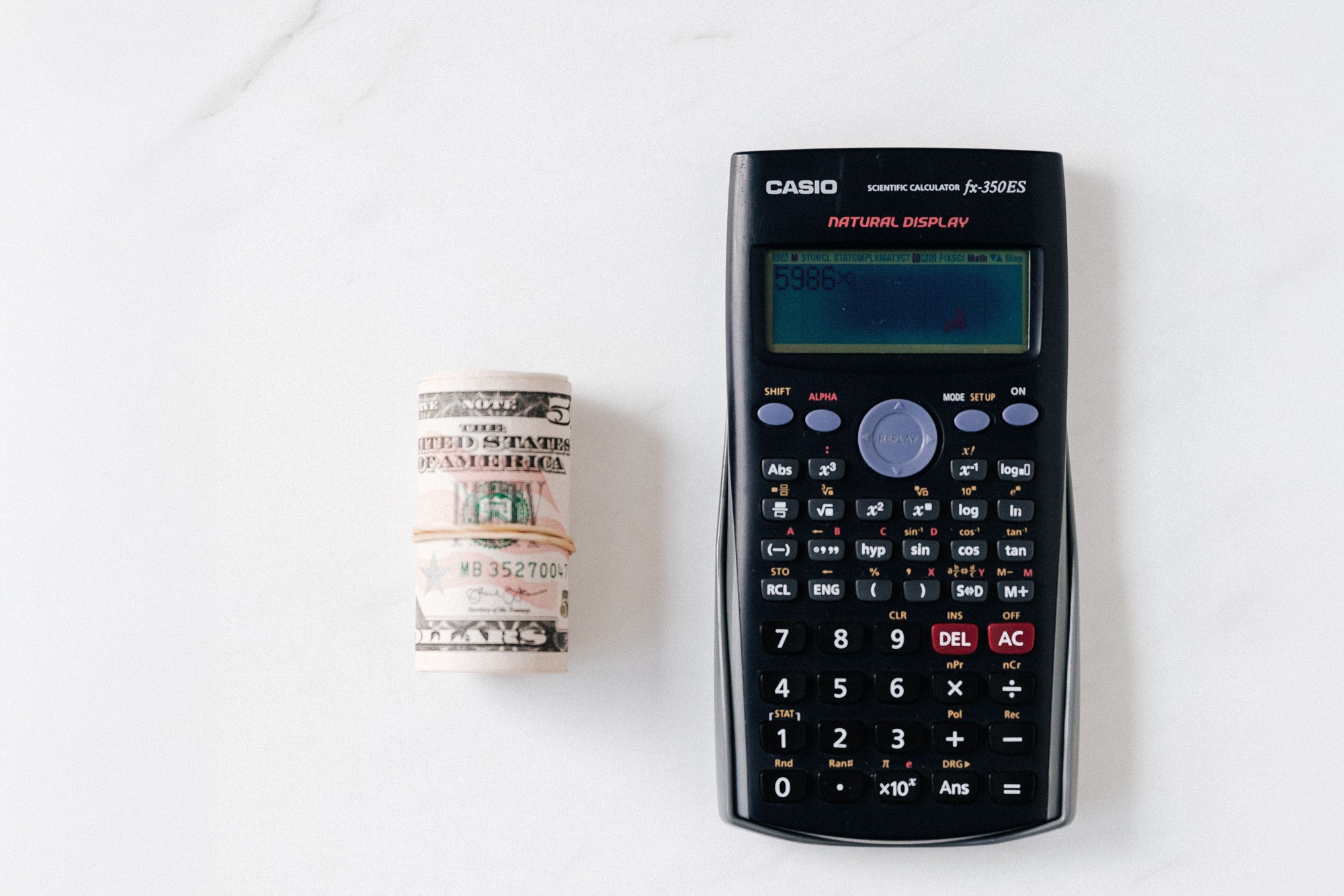 Calculator and rolled dollar bill illustrating how to increase website conversions through conversion rate optimization.