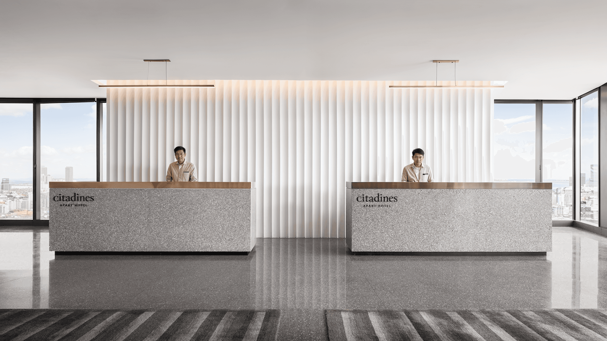 Interior design of a spacious open-plan office at ULS, featuring concrete floors, glass partitions, light wood furniture, and abundant greenery.