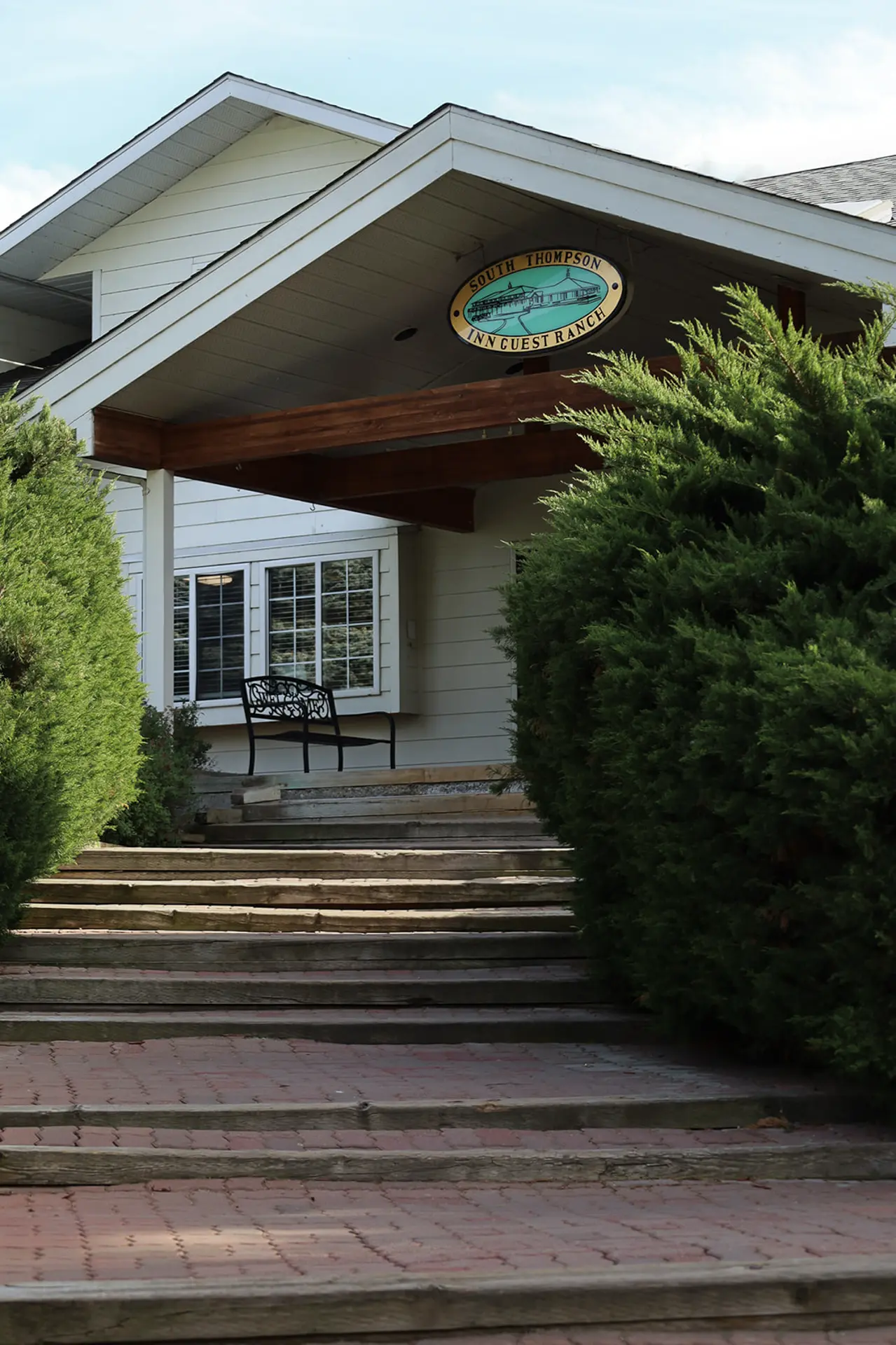 Exterior of South Thompson Inn Guest Ranch with sign and stairs.