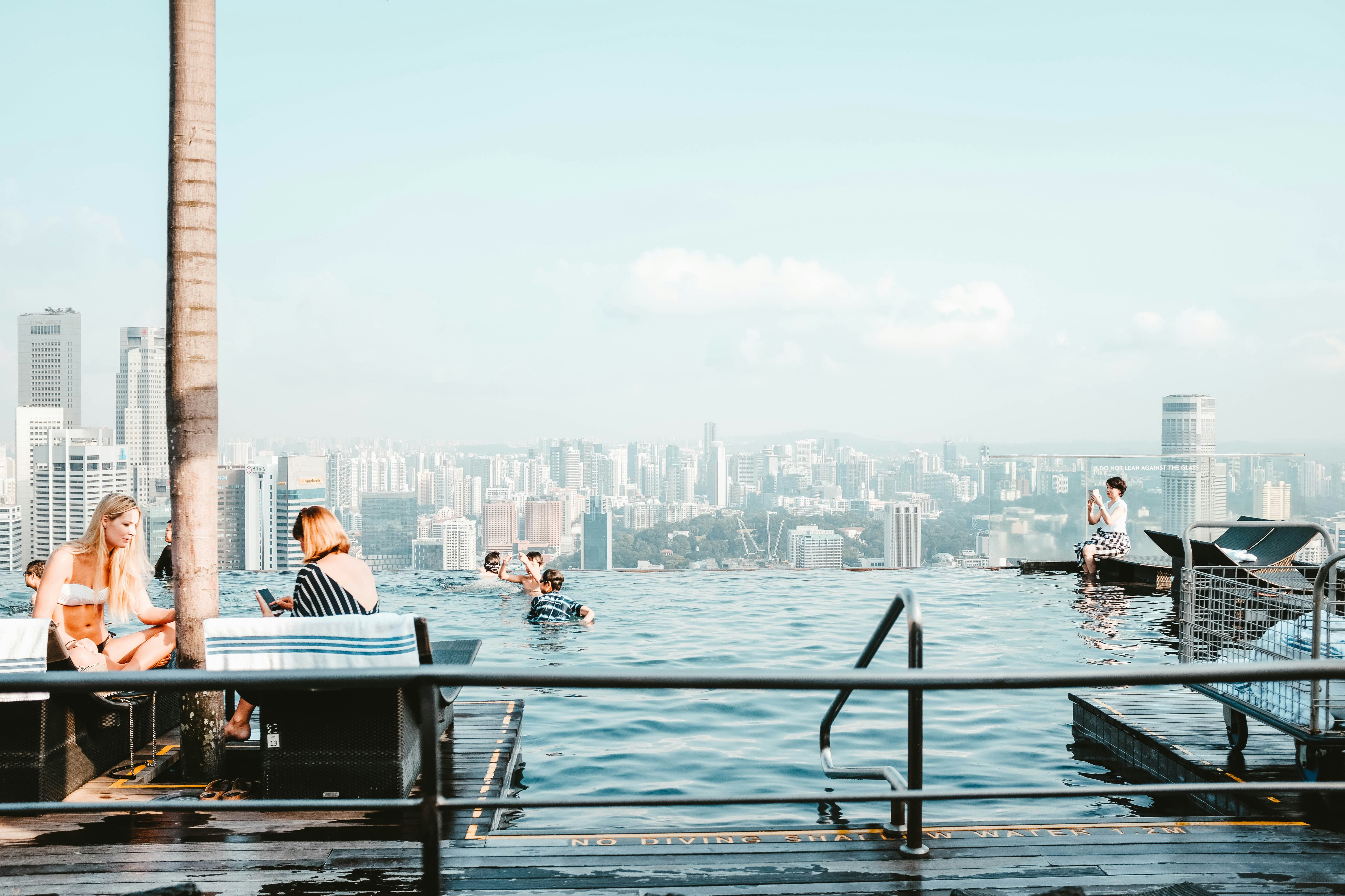 People swimming in a rooftop pool with a view of the city. 