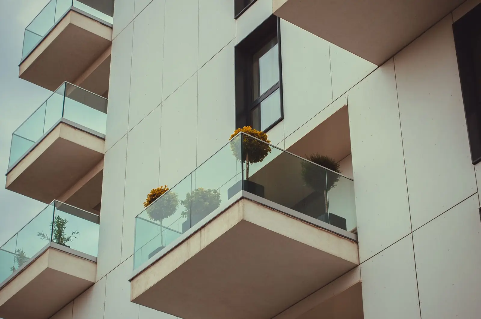 Glass balconies with plants on a white apartment building