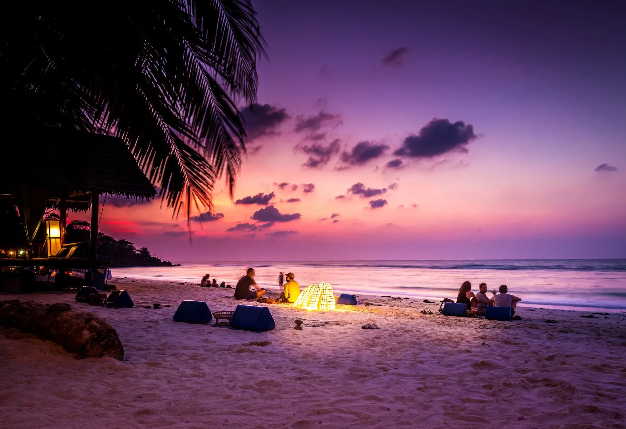People relaxing on a beach under a purple sky