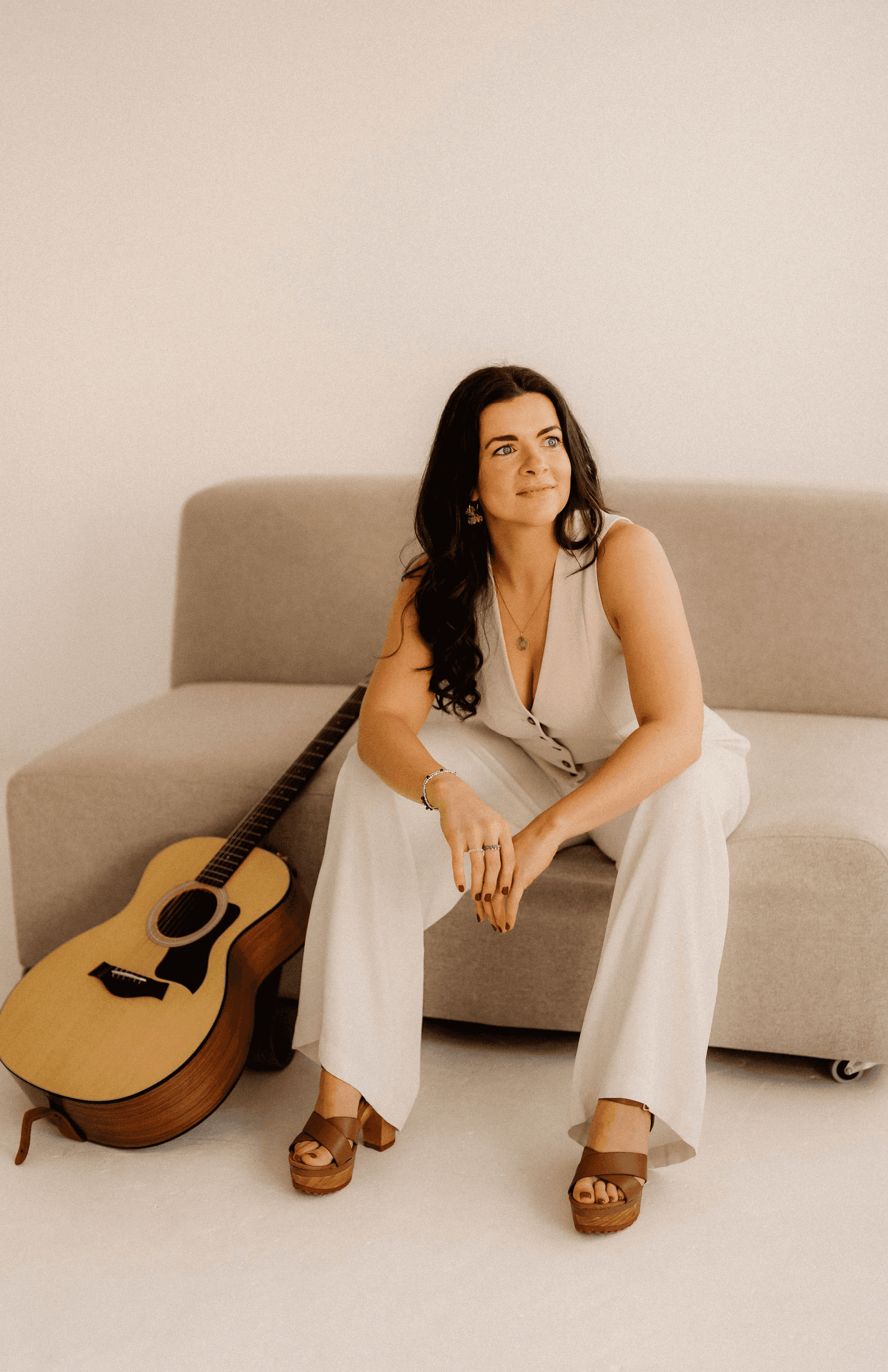 Maria Wiethaler freie Rednerin und Sängerin für Hochzeiten, Taufen, Trauerfeiern und Events aus München und Landshuter Umgebung. ine lächelnde Musikerin mit langen, dunklen Haaren spielt eine Akustikgitarre und singt in ein Mikrofon. Sie trägt ein glitzerndes Oberteil und einen fließenden Rock, während sie im Sonnenlicht auf einer Bühne oder einem erhöhten Außenbereich auftritt. Im Hintergrund ist ein Geländer mit leicht verschwommenem Ausblick auf die Umgebung zu sehen.