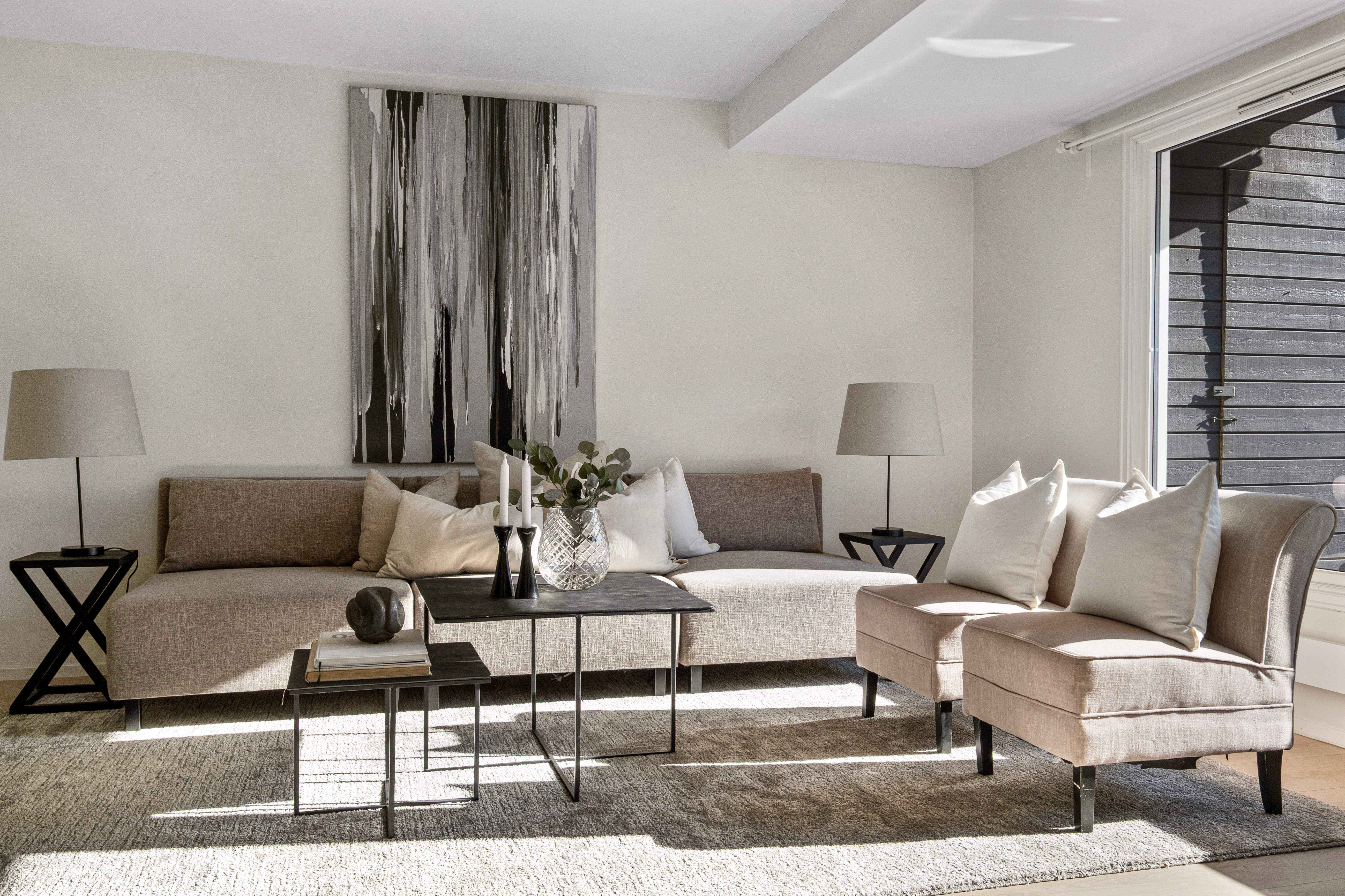 Lys stue med sofa, bord og gardiner i nøytrale farger