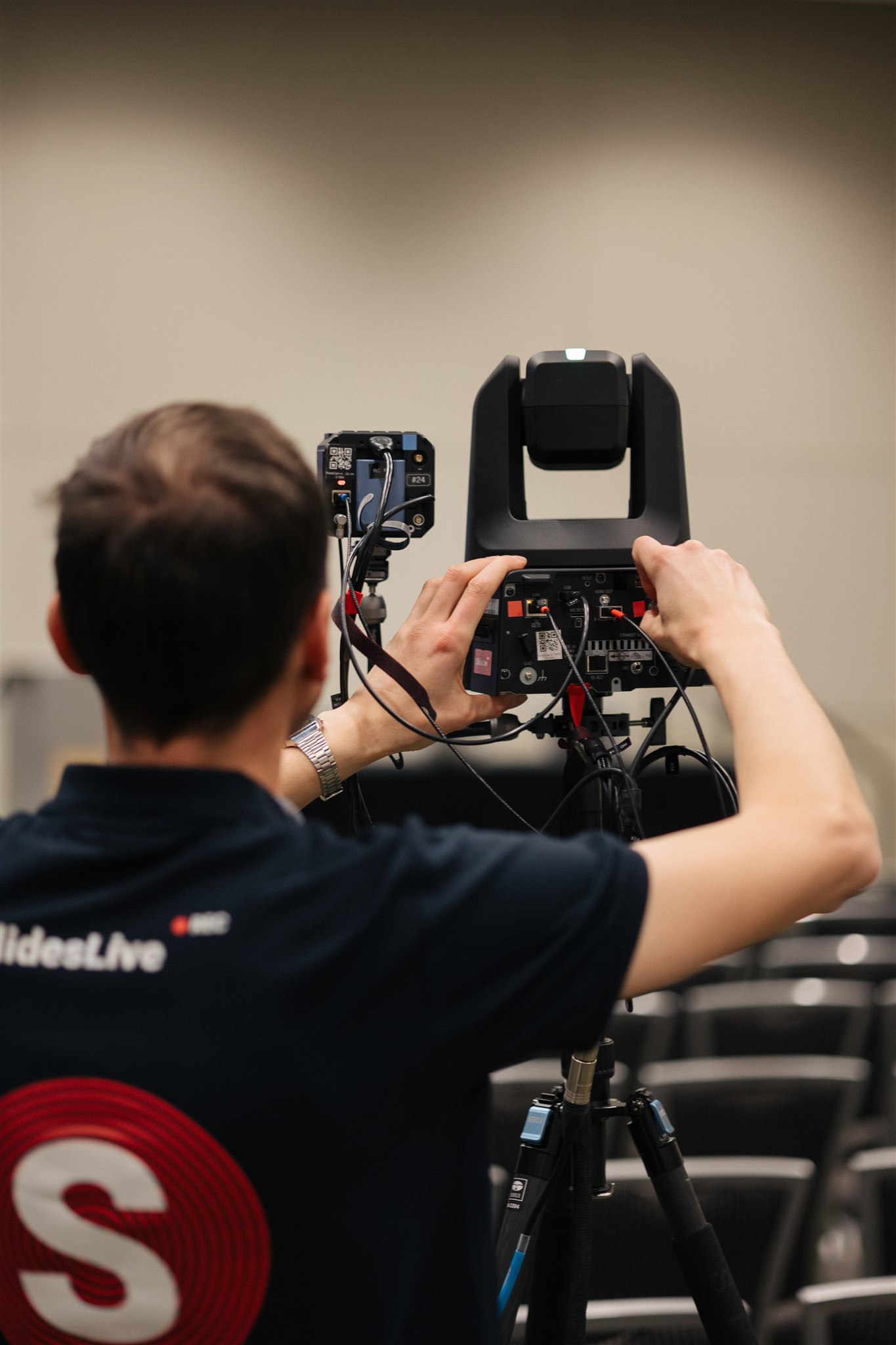 SlidesLive technician seen from behind while installing a robotic camera system.