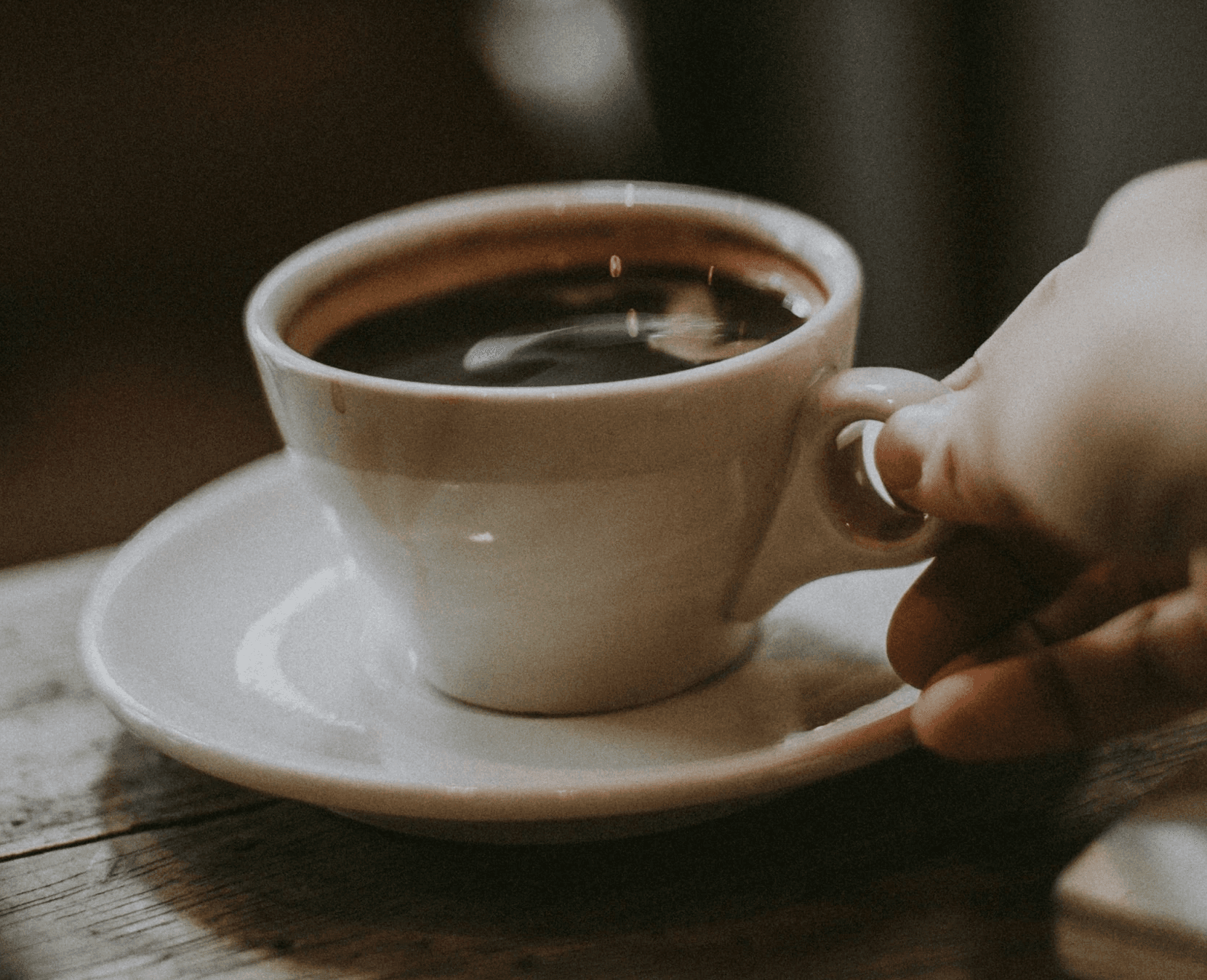 person holding white ceramic cup with liquid