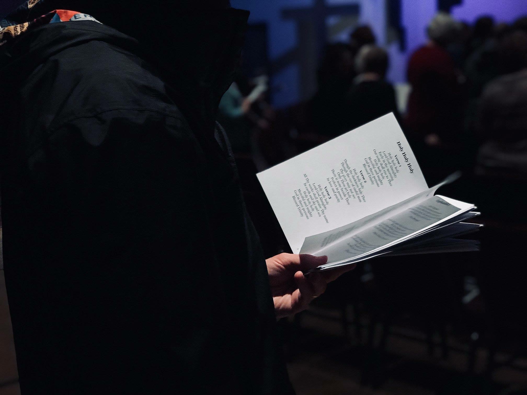 person holding a book in church - how to write gospel songs