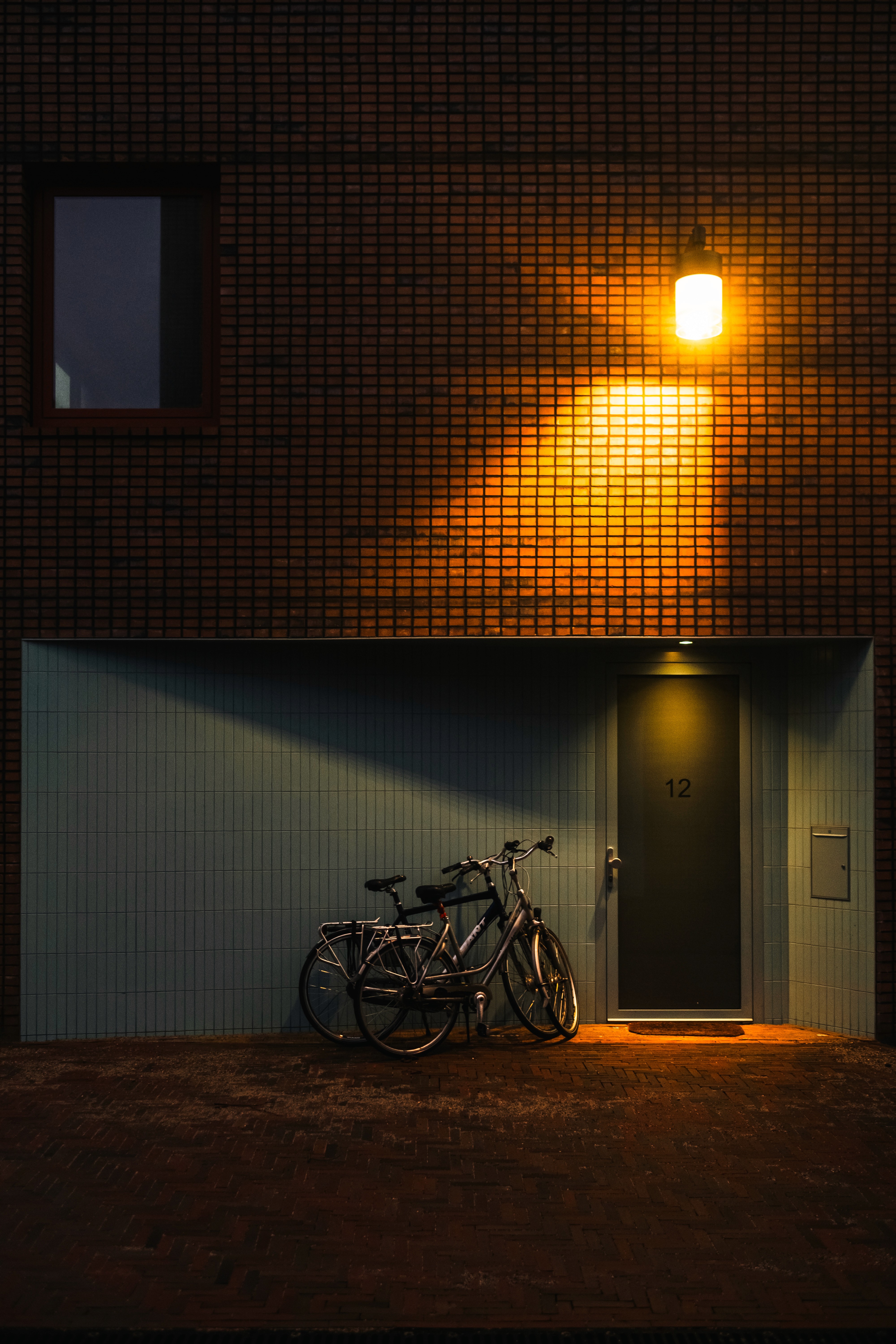 Dutch house front facade warmly lit by a streetlight, with bikes parked in front