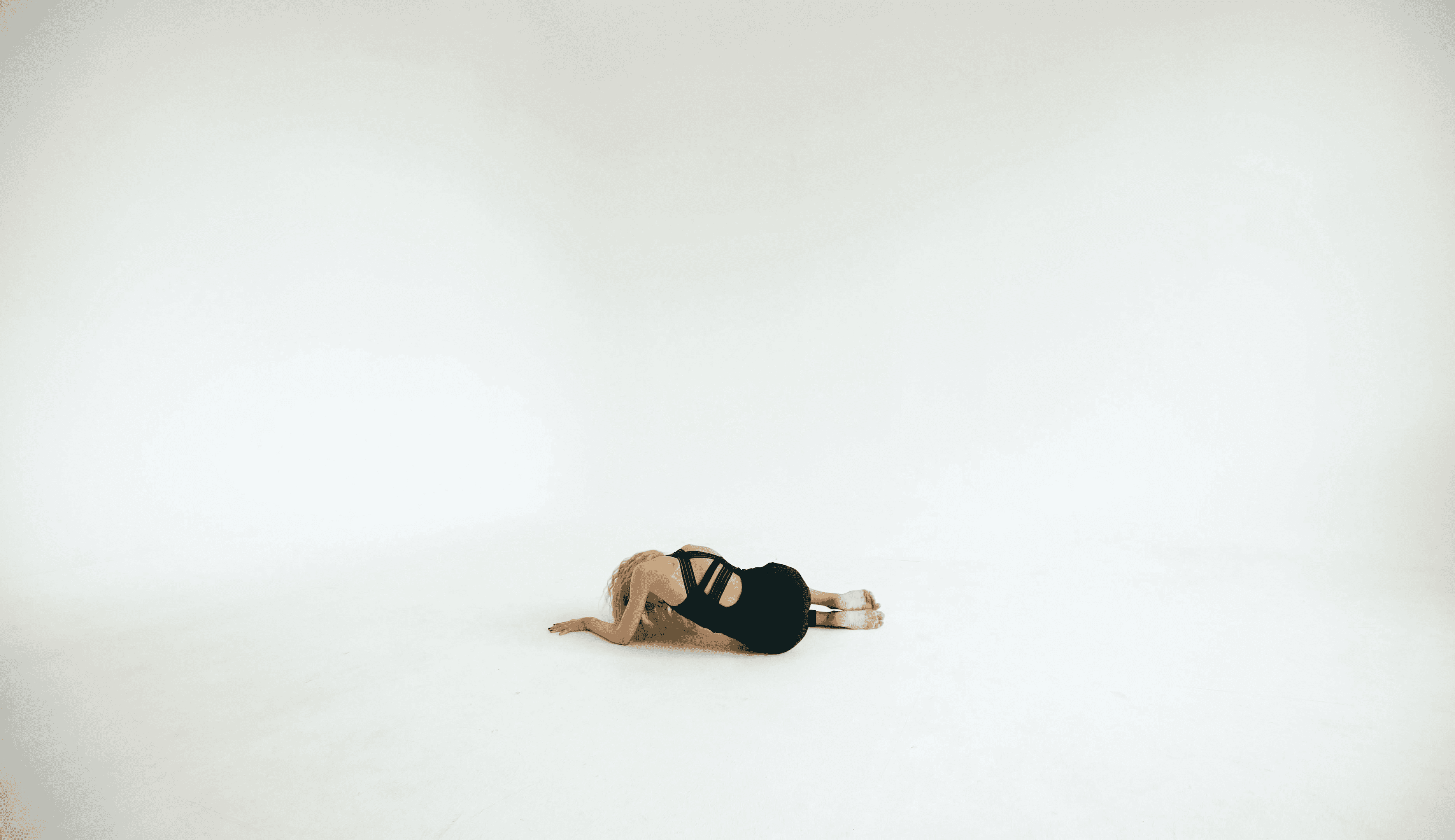 A dancer lies on the floor in a studio.