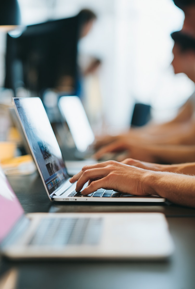 Hands typing on a laptop keyboard in a working studio environment.