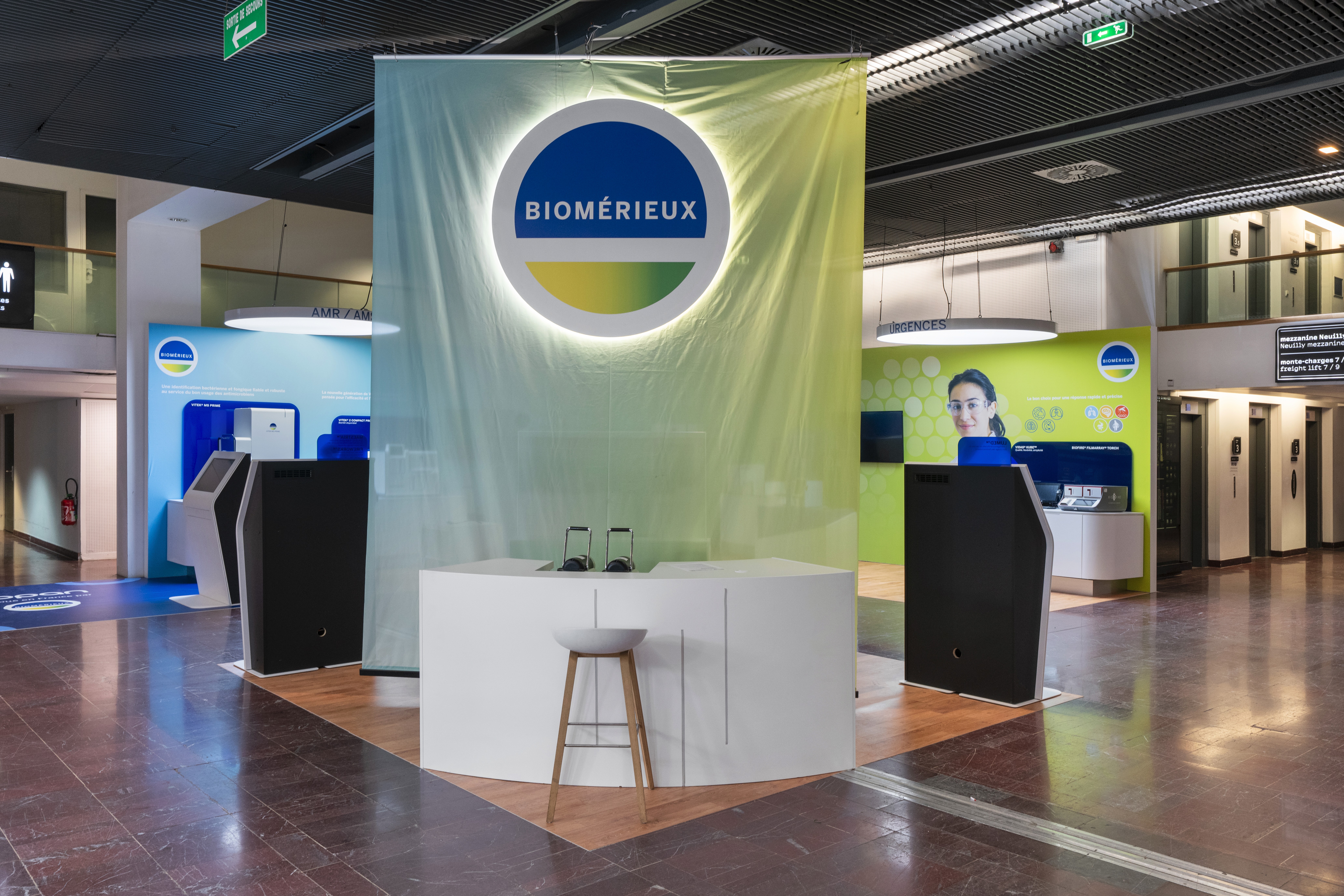 Stand bioMérieux RICAI 2025 réalisé par Expace – vue panoramique du stand avec totem numérique interactif, zones AMR/AMS et Urgences colorées et présentation automates diagnostic in vitro