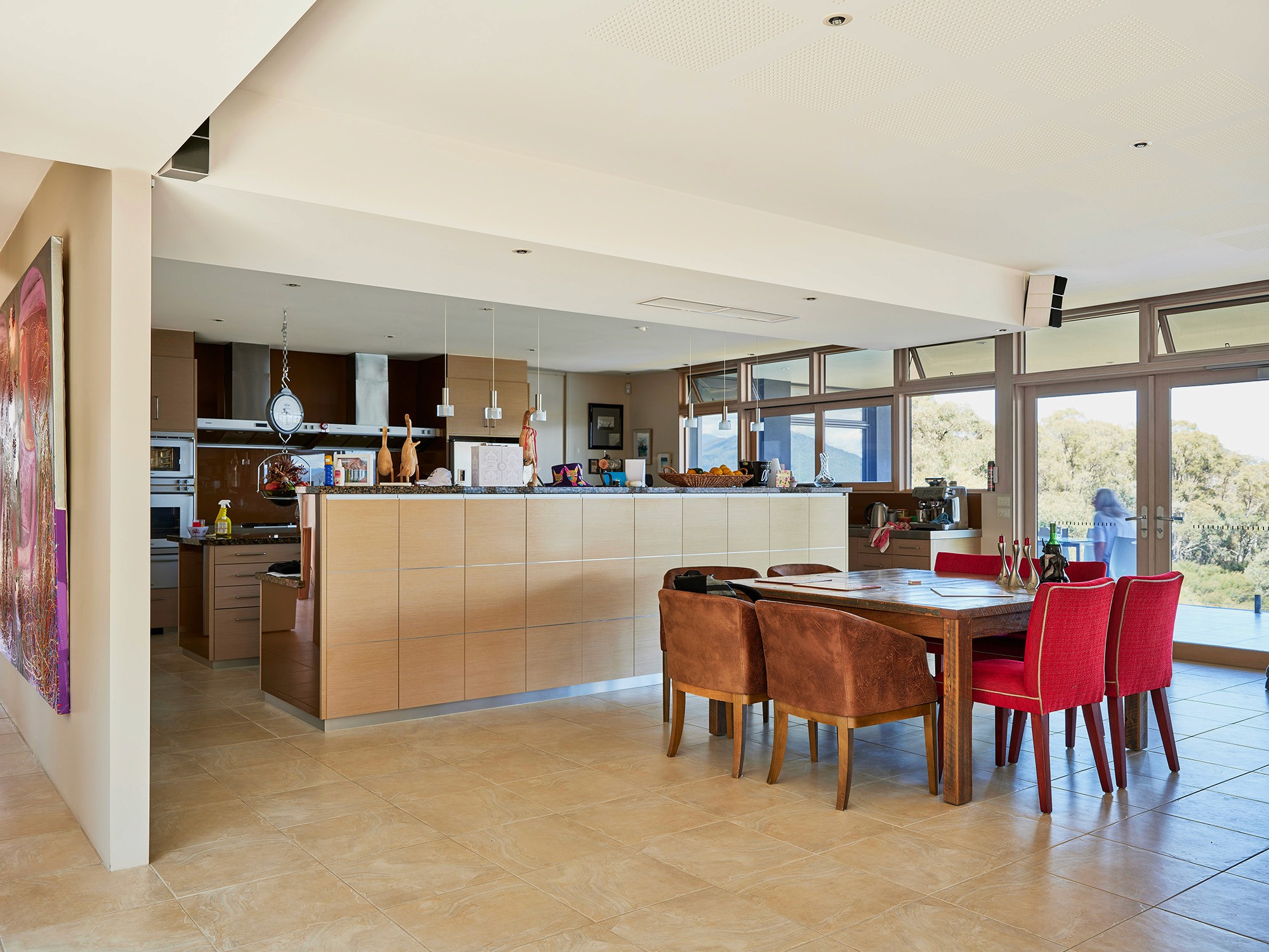 Modern kitchen and dining area with wood cabinets and large windows