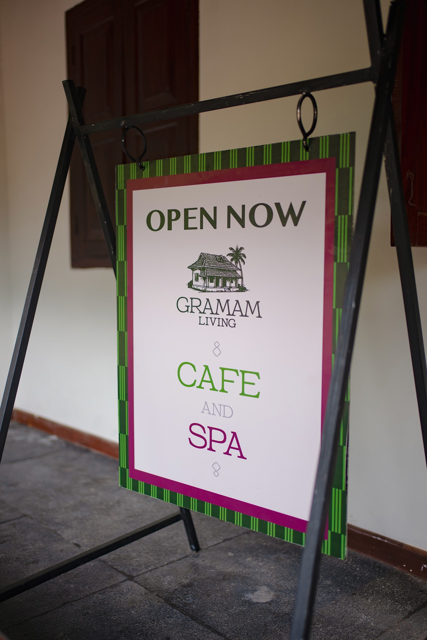 A serene and elegant spa space with wooden reclining chairs and white cushions. Golden sunlight filters through a cascading water feature, creating a peaceful atmosphere. Tropical plants and candles add to the relaxing ambiance.
