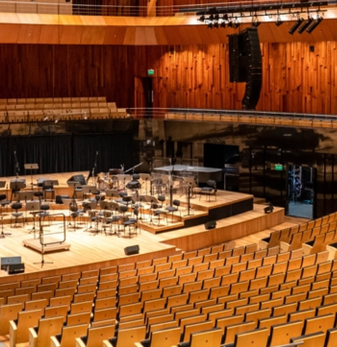 A spacious concert hall with empty rows of seating, showcasing a stage set for an orchestra performance.