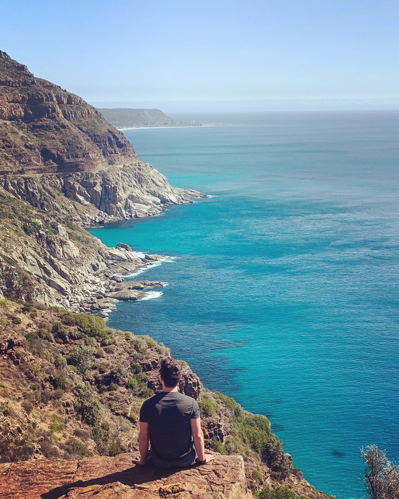 Scenic coastal view with Adam sitting on a cliff edge, inviting users to connect