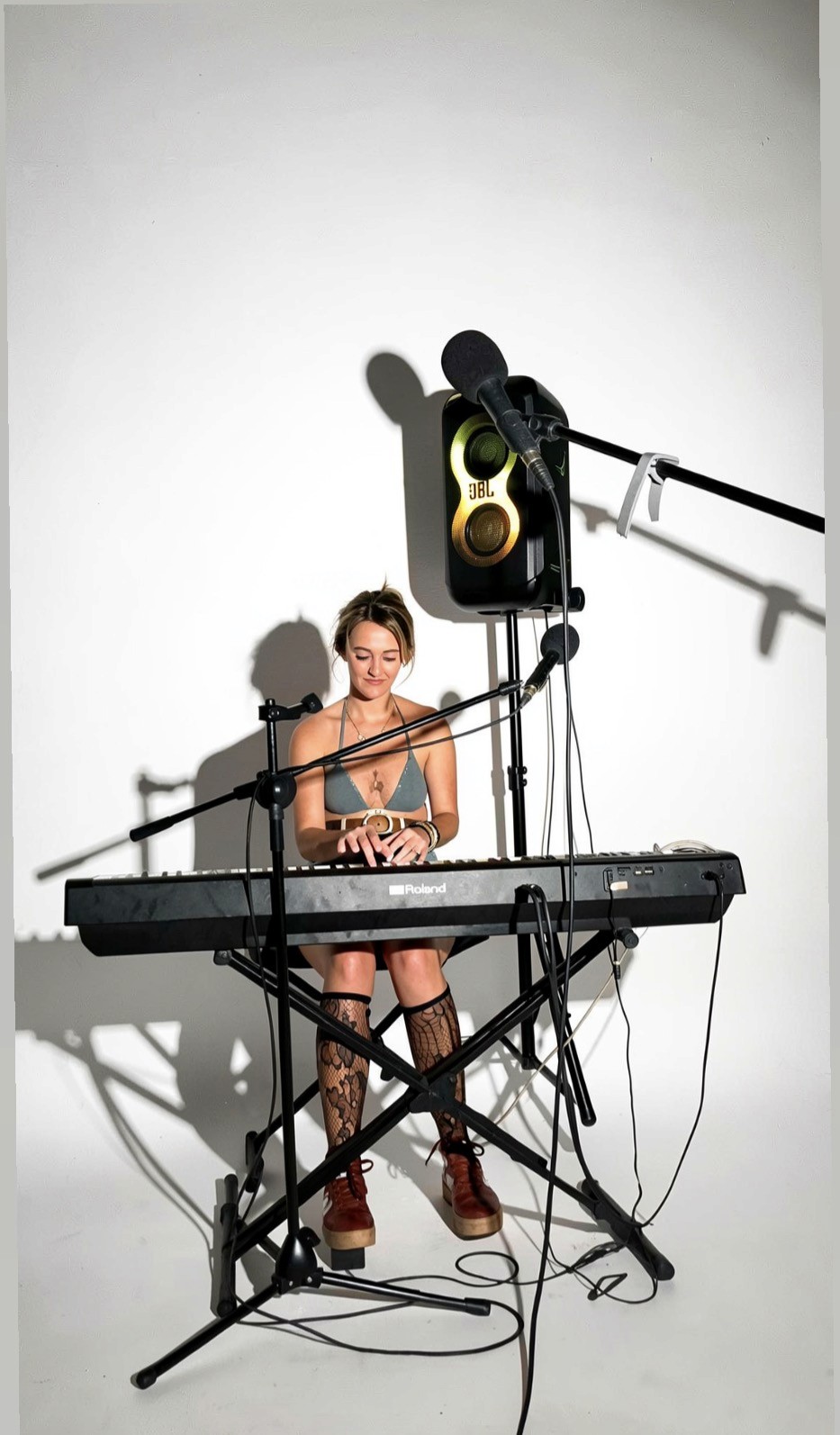 Cassandra Winegard performing original music at a keyboard with microphones and speakers.