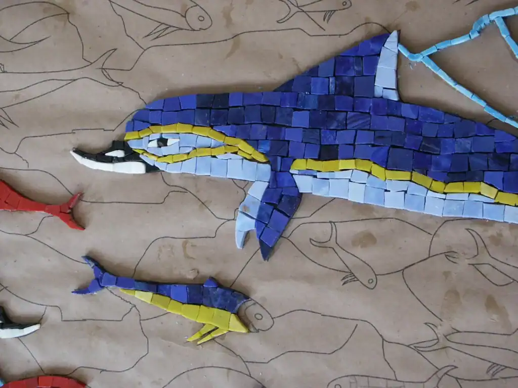 Colorful mosaic blue whale sculpture with detailed tile work.