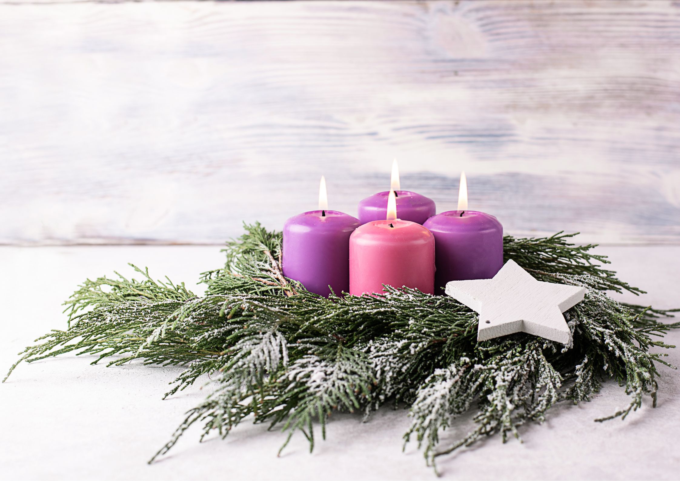 Velas de adviento encendidas en corona natural