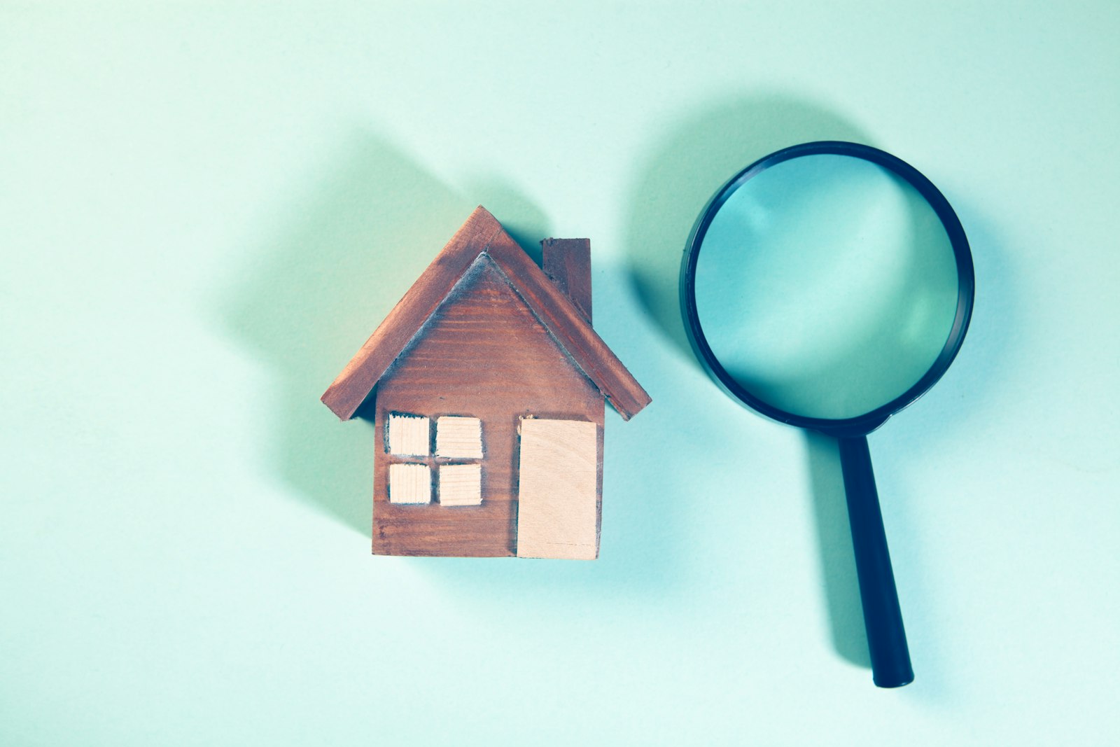 Magnifying glass held over a small model house