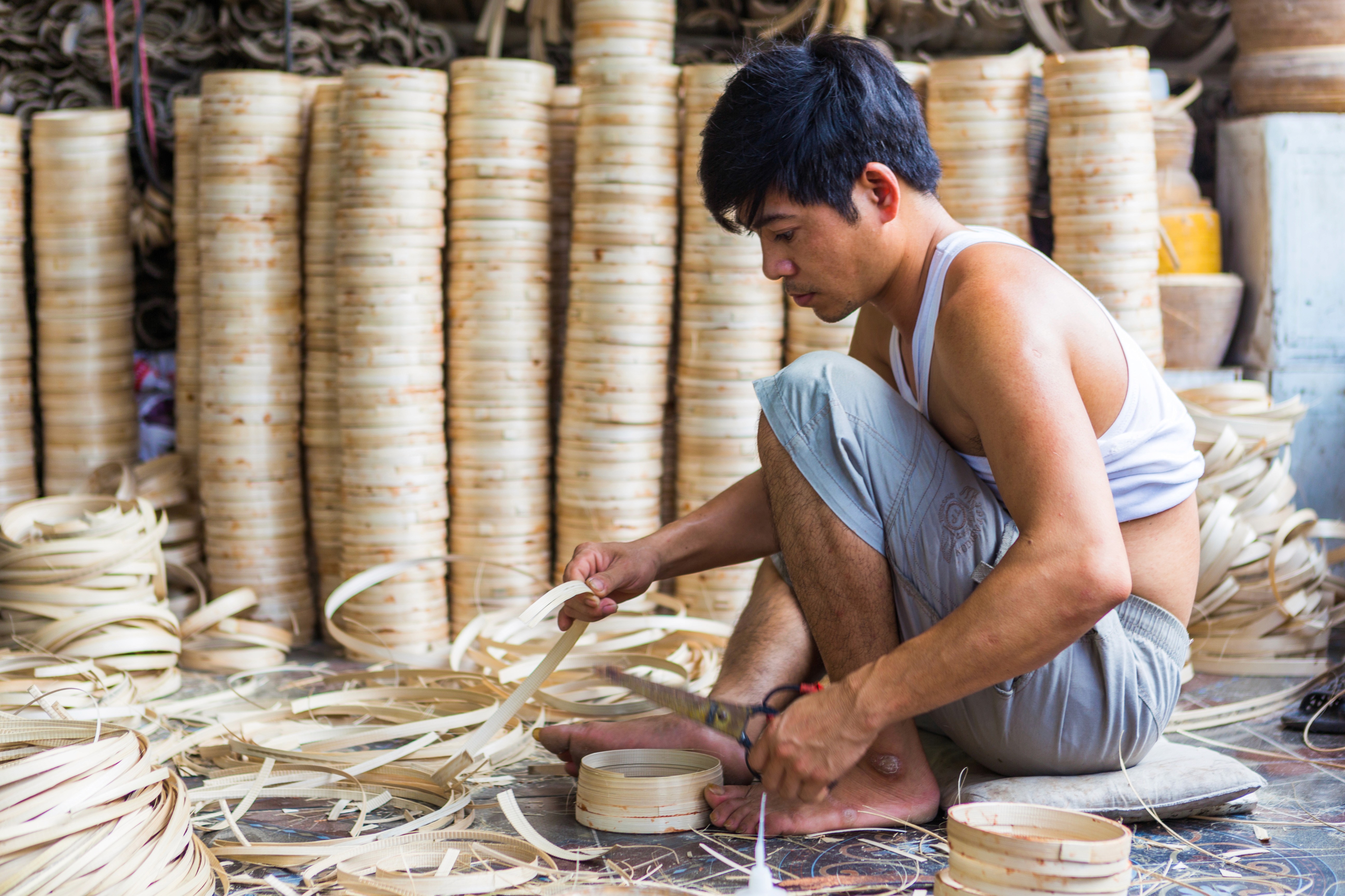 Vietnamese factory worker cutting bamboo strips to size