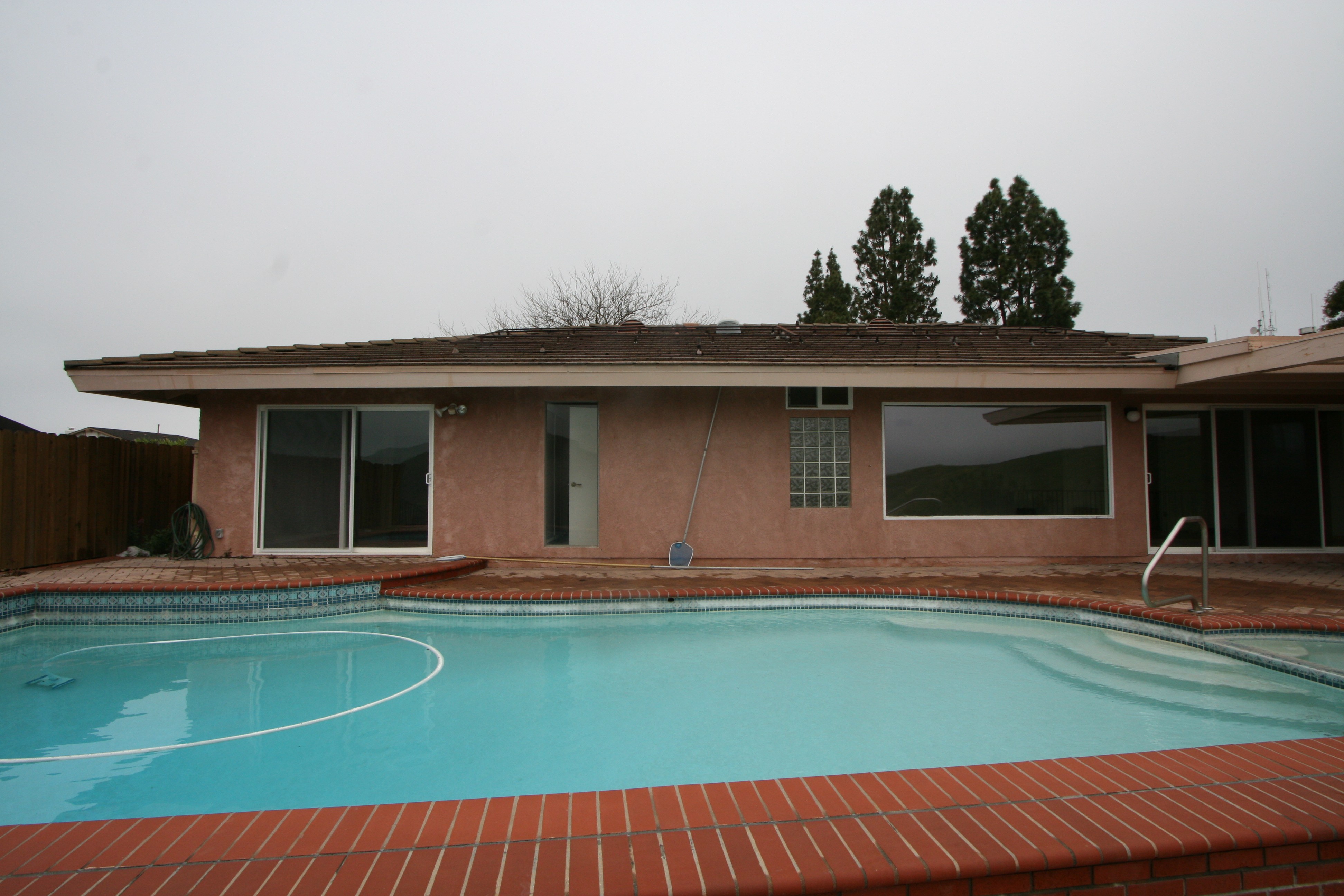 Before photo of an old ranch-style backyard featuring a pool.