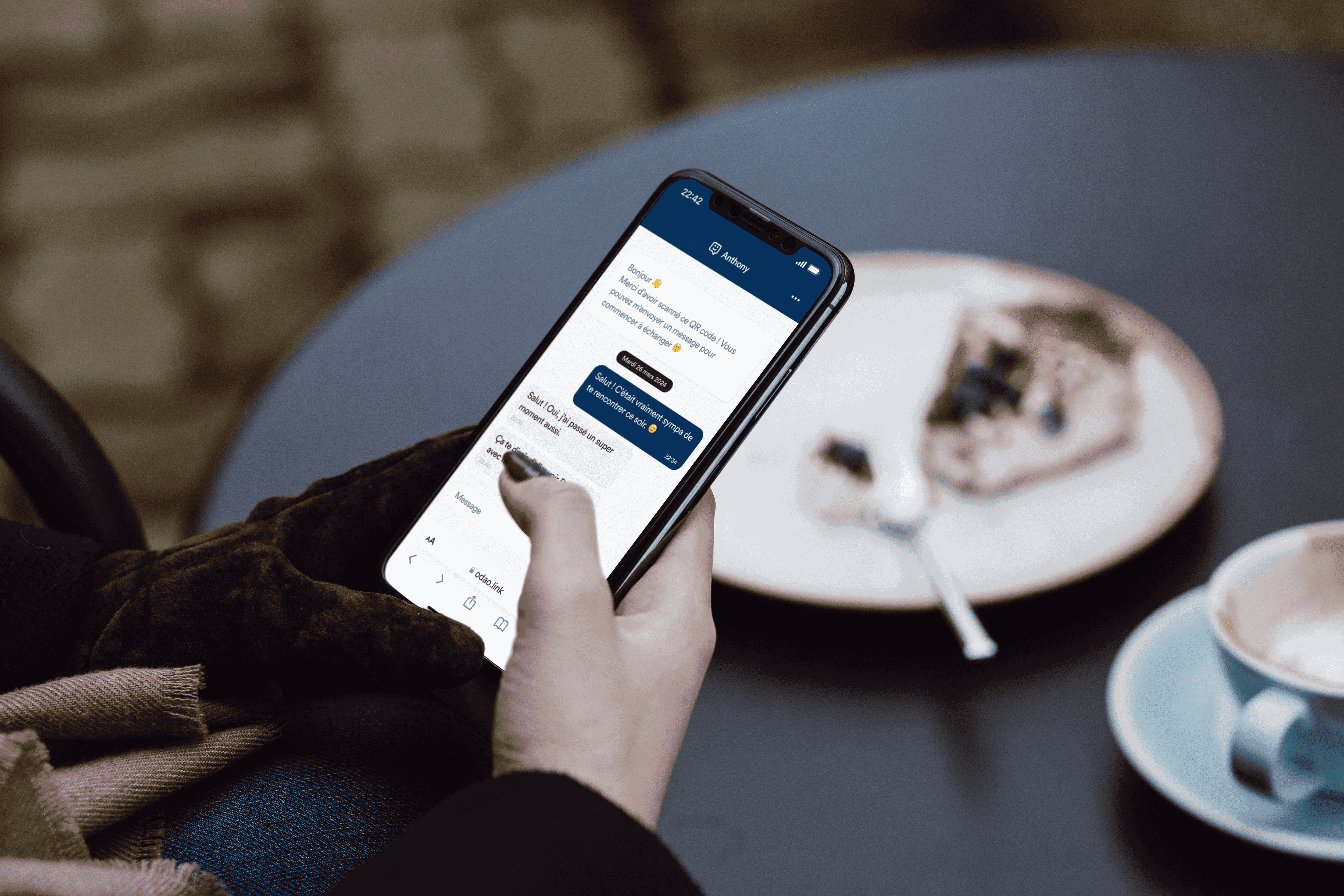Photo d'une personne, assise à une table d'un café, en train d'écrire un message via la solution ODAO.