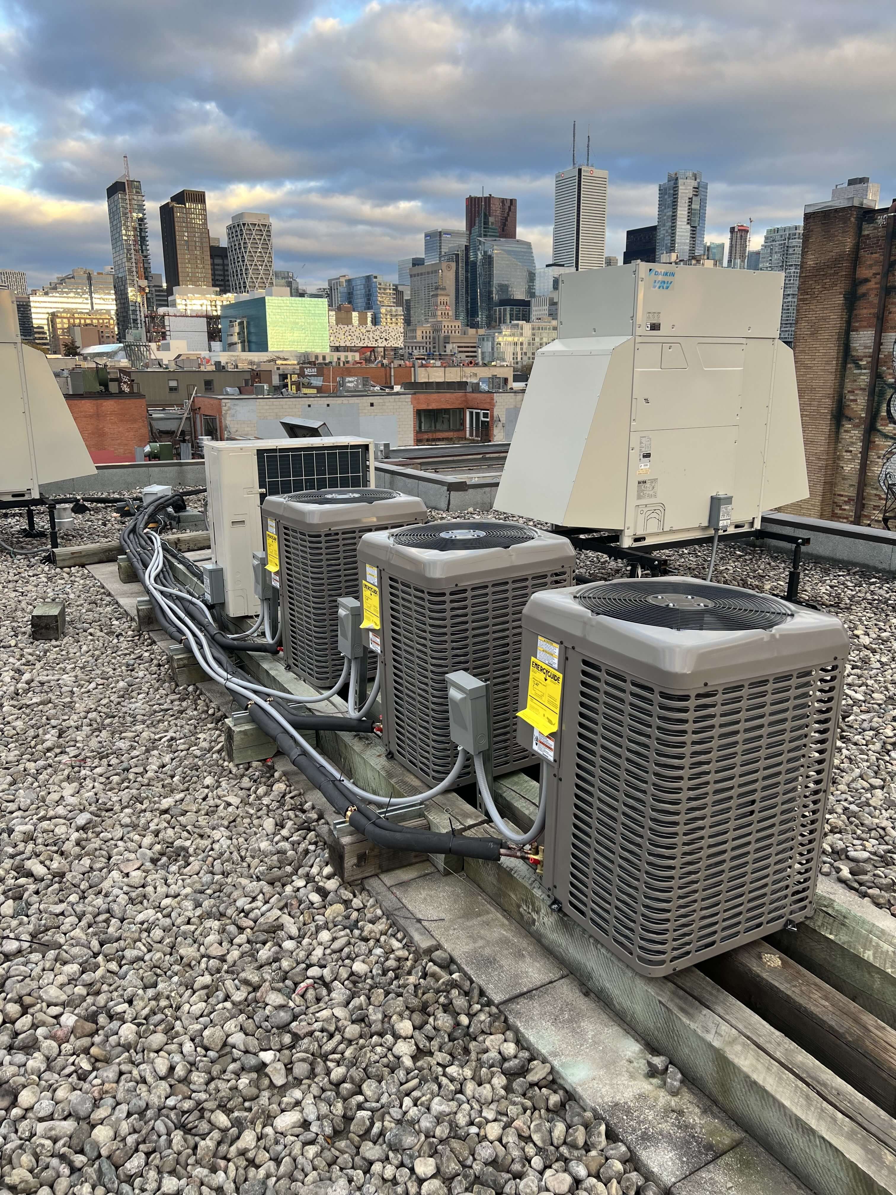 three Air conditioner units freshly installed on top of an industrial building in down town mississauga