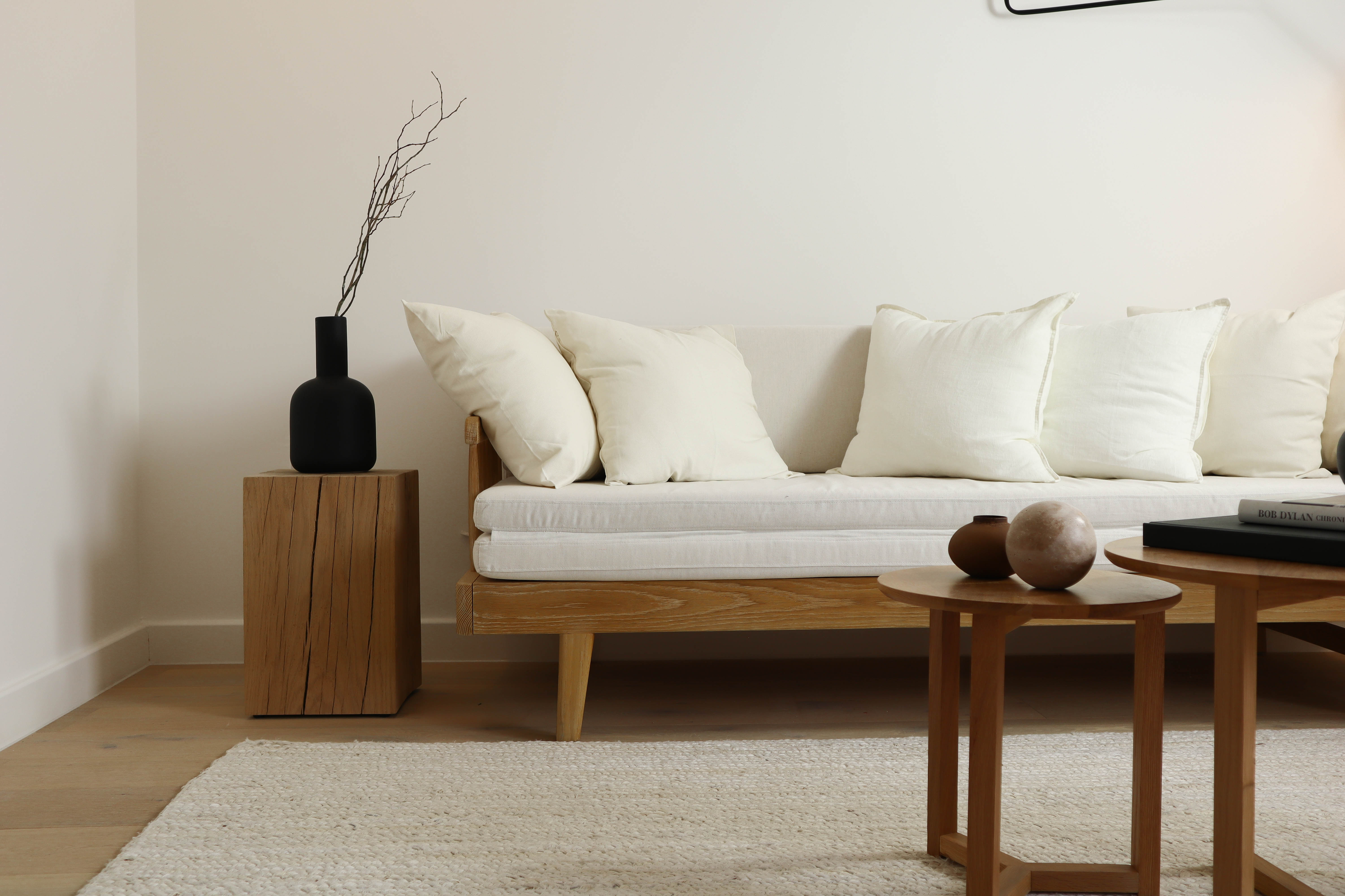 Minimalist nordic-inspired white couch with black vase on a side table