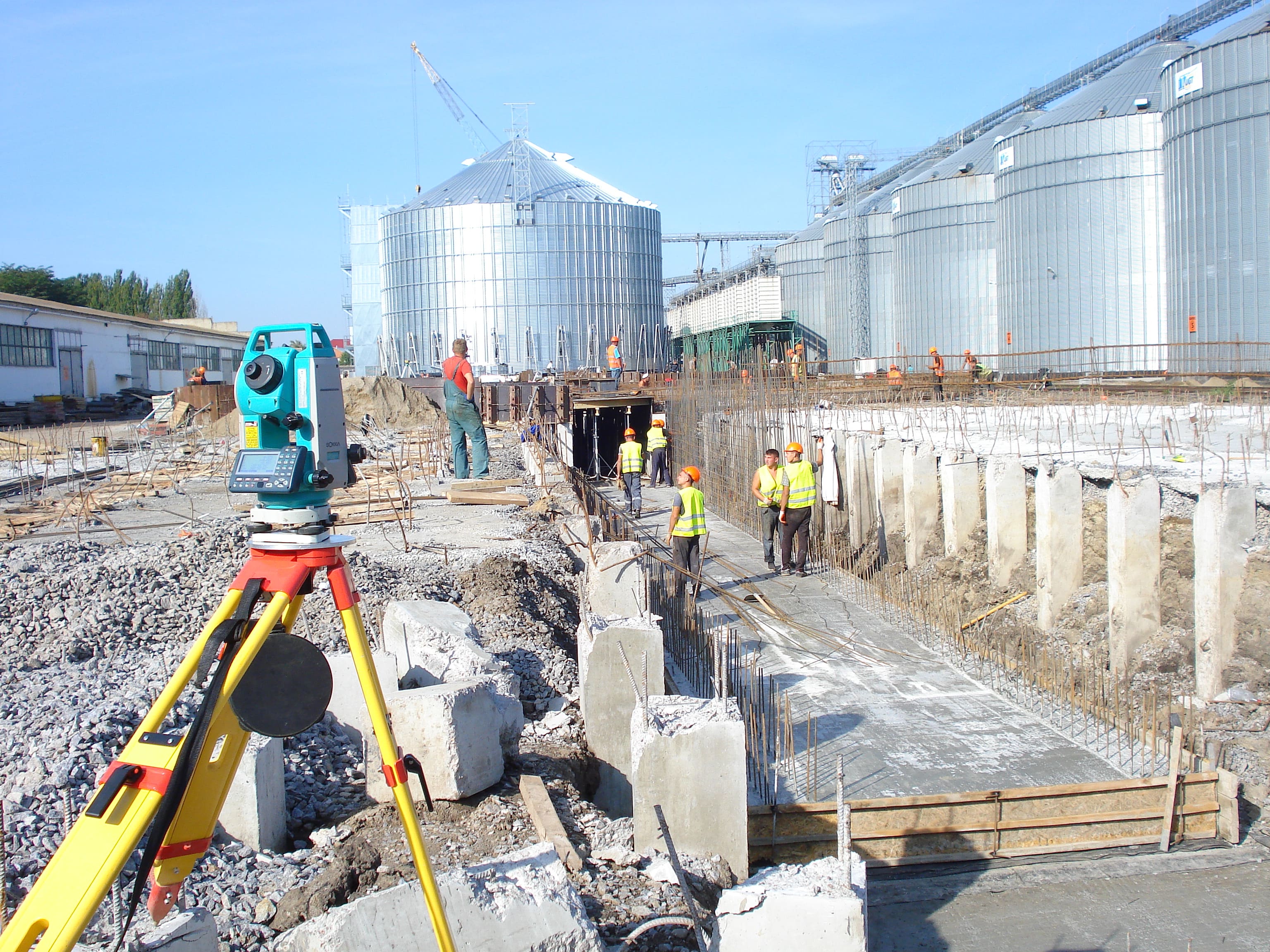 Група геодезистів на будівництві, пристрій, котлован на фоні