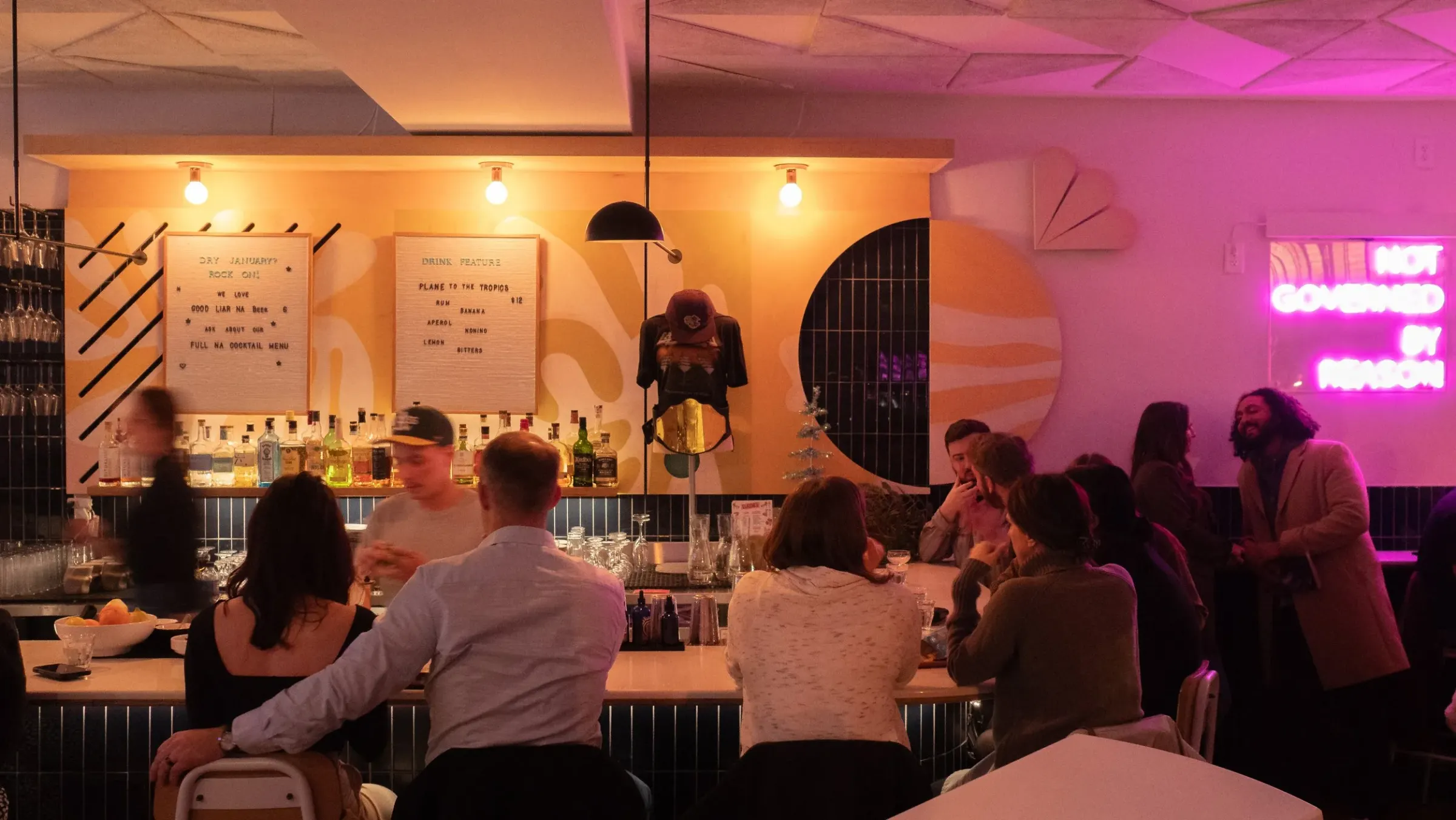Guests at the bar under pink neon at Law Bird
