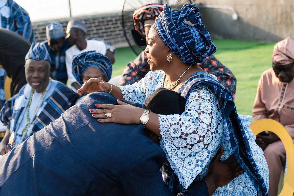 Luxury wedding planned by Victoria Brooks Events in Nigeria with elegant décor and beautiful reception. Groom in a blue suit and bride in a white wedding dress with flowers surrounded by family and friends.