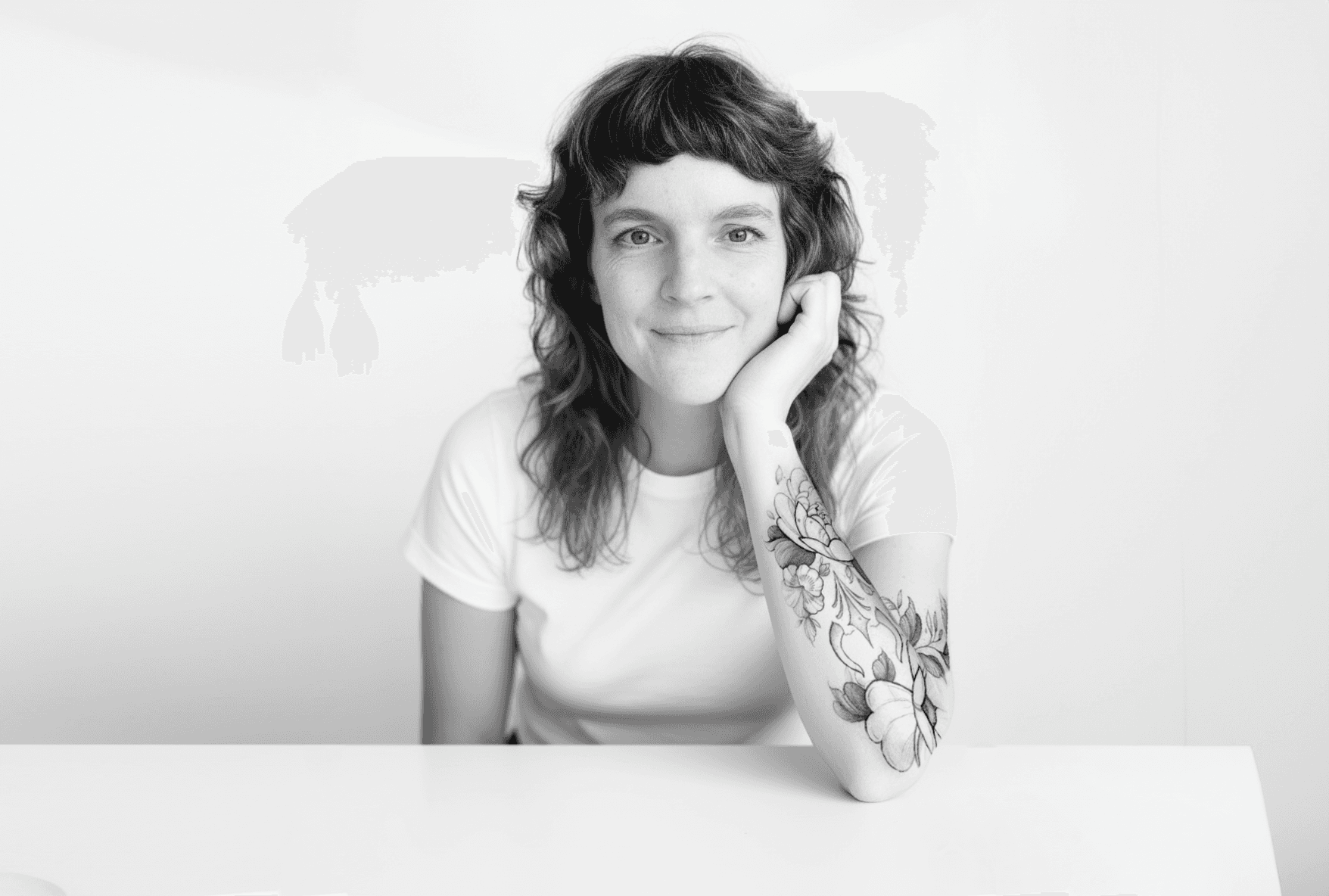 Black and white image of people working at a table with laptops, showing hands gesturing during discussion of digital content displayed on screens, with fabrica® logo in the corner.