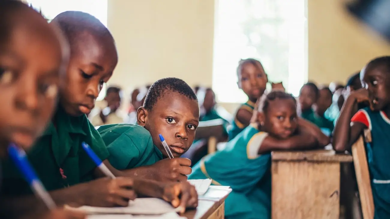 Schoolchildren in Tanzania, dressed in green uniforms, focus on learning in a classroom environment. This picture illustrates the impact of the Kick for Life Foundation, which improves educational opportunities in underserved regions of Tanzania.