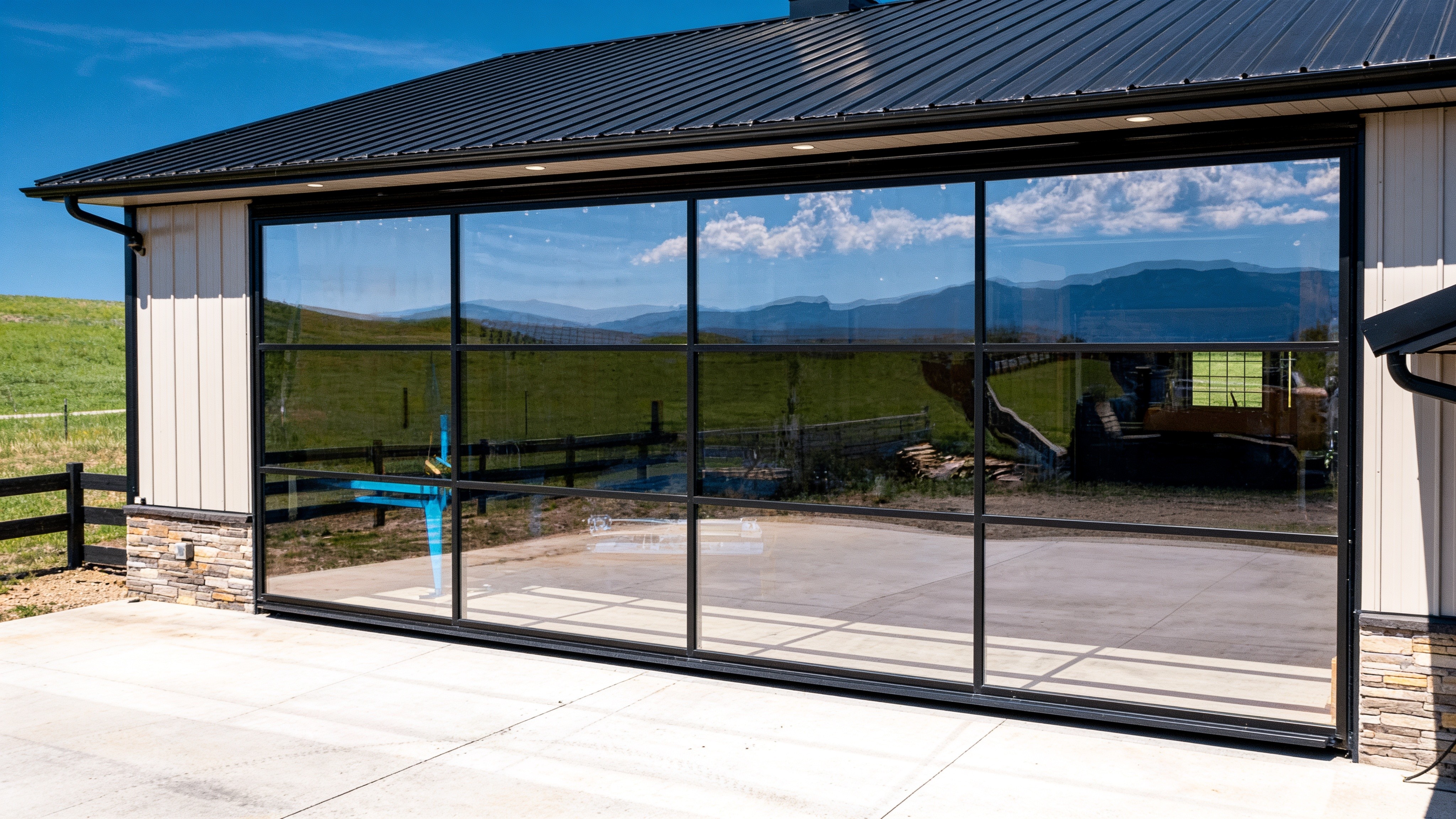 Black-framed glass hydraulic garage door on a modern home with mountain views