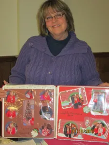 Woman in a purple sweater showing a red holiday scrapbook layout