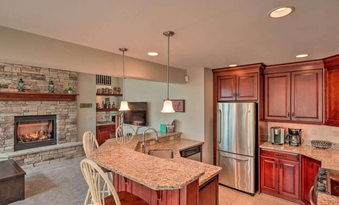Kitchen with granite high-top bar, cherry cabinets and stainless fridge at SummitWind