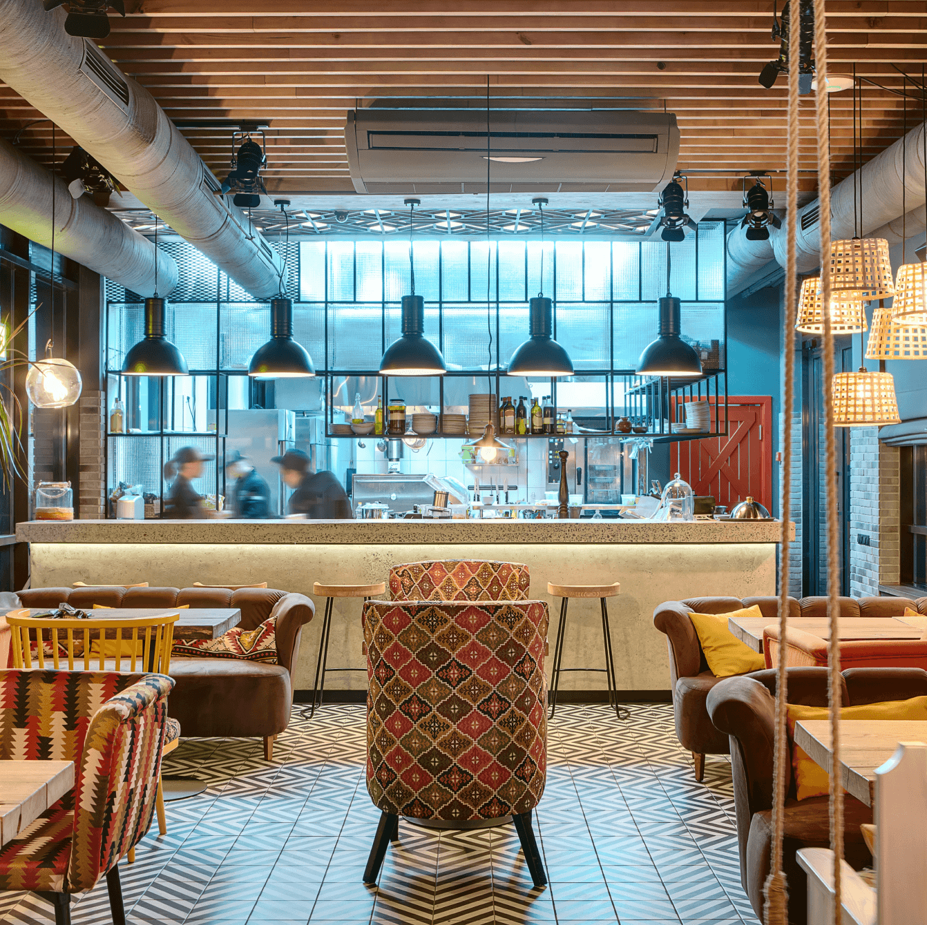 Espace lounge accueillant d'un café-restaurant avec des canapés confortables, une lumière tamisée et une vue sur le bar en béton.