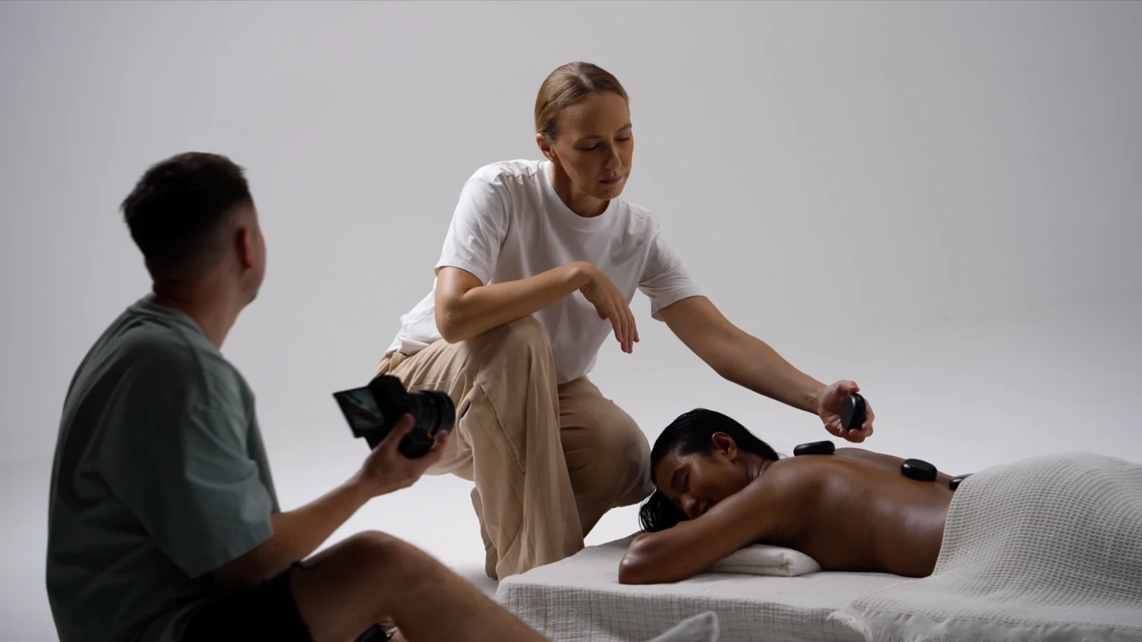 Hot stones placed on the model's back while the photographer captures behind the scenes