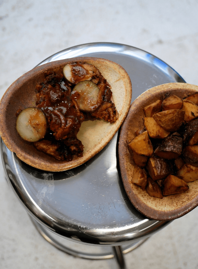Assiette de poulet croustillant avec sauce épicée et pickles, servie avec des pommes de terre dorées au restaurant latino Compadre à Paris.