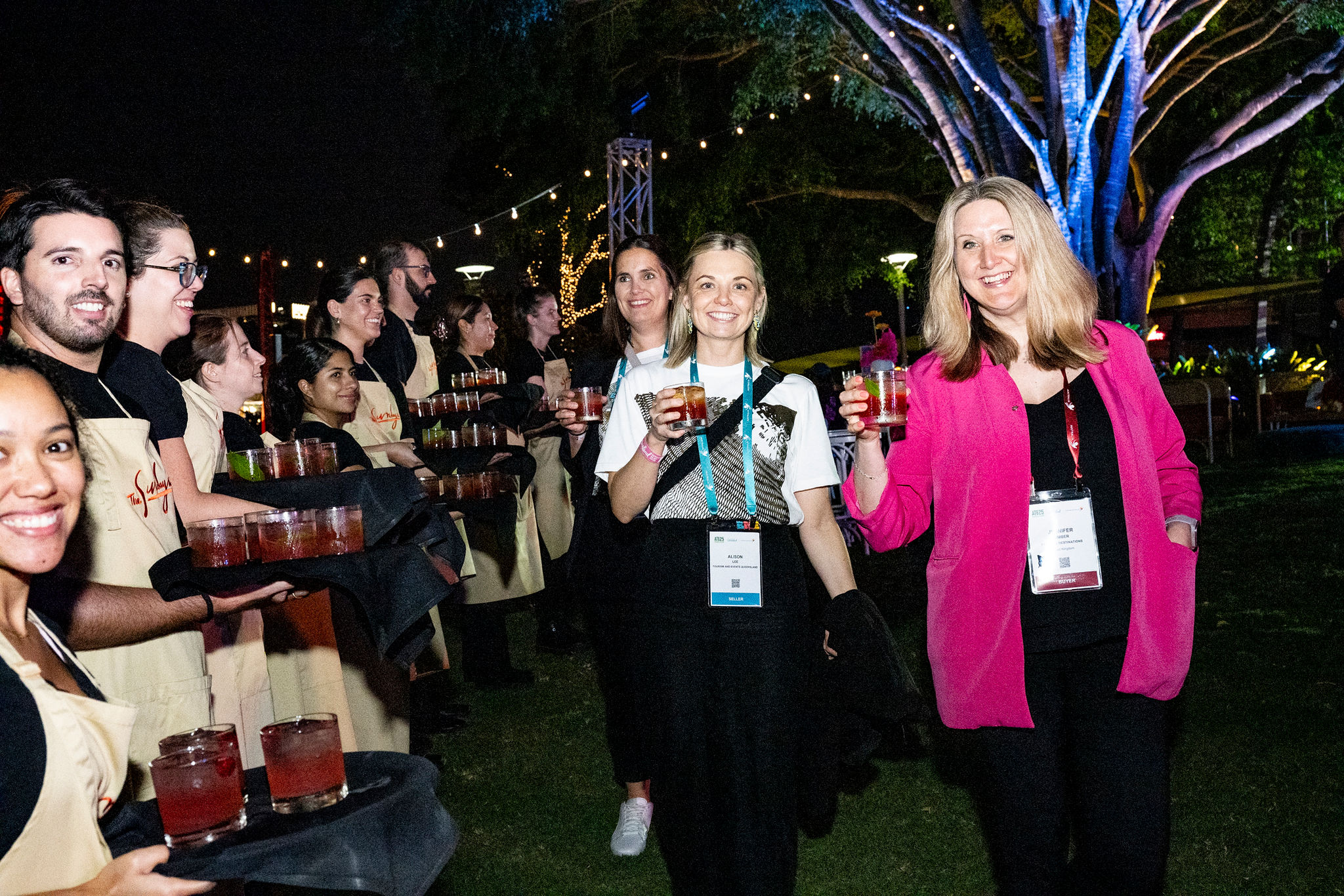 Guests arriving at an outdoor event, greeted by tray service of cocktails