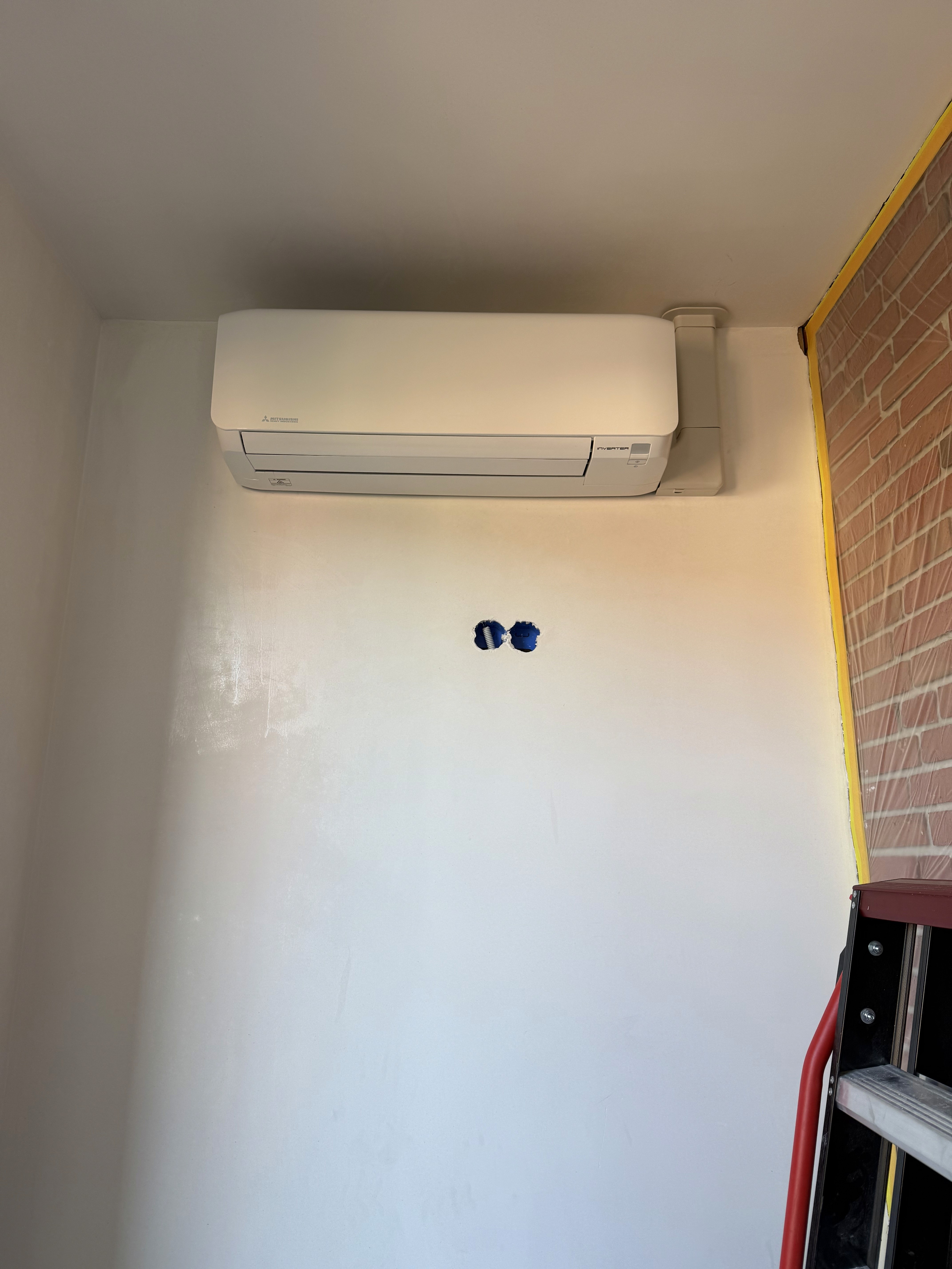 Monteur installeert split-unit airco aan de muur in een moderne woonkamer