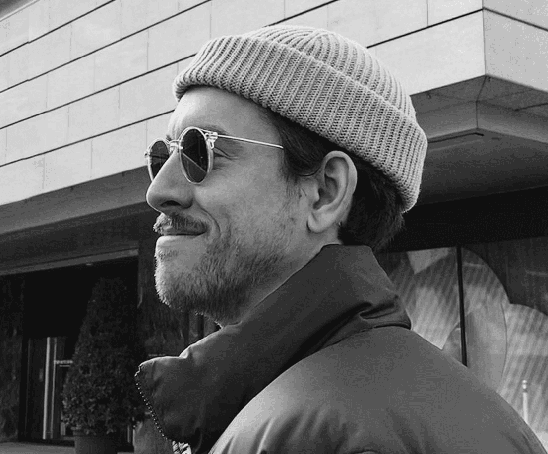 A close-up of a hand wearing multiple decorative rings against a blue background.