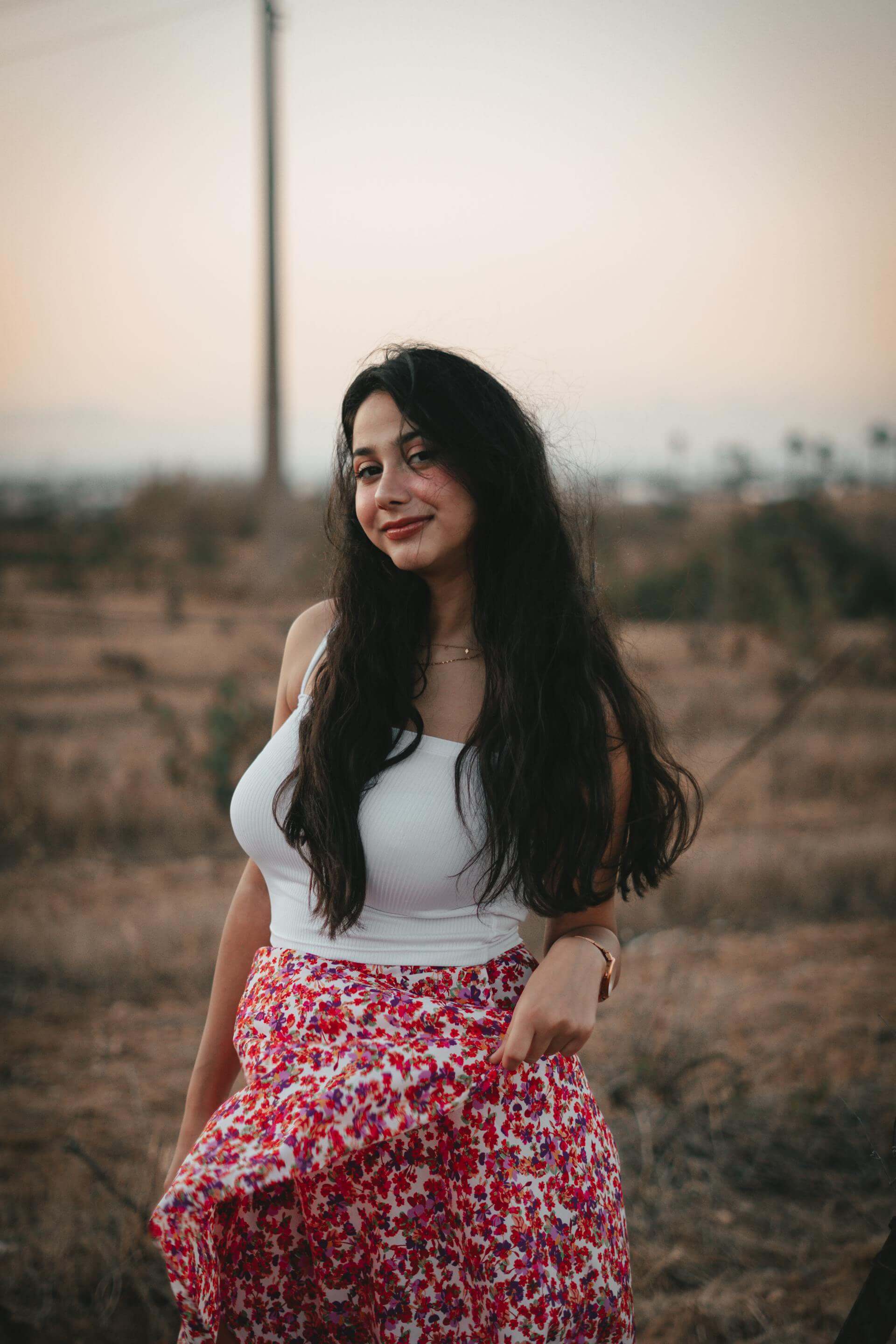 A woman in a floral skirt stands gracefully in the center of a vibrant field, surrounded by lush greenery