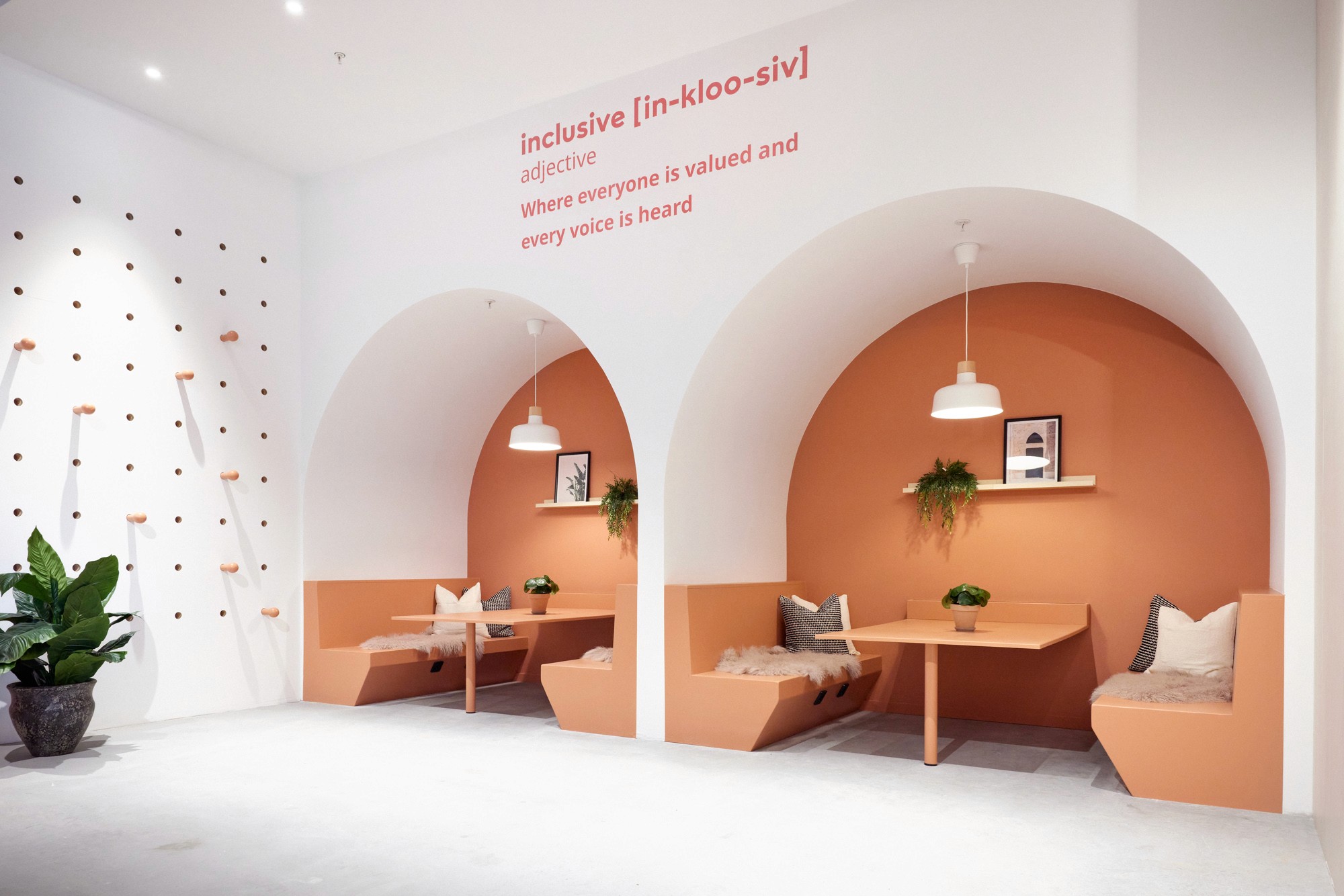 Modern red brick apartment or office building viewed from below against a blue sky, showcasing its geometric architecture with evenly spaced windows and balconies.